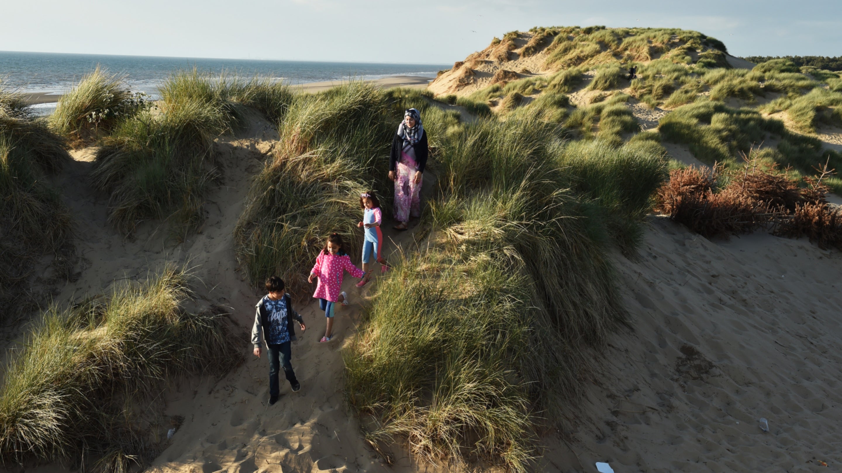 A lady and three children enjoying a walk through the dunes at Formby