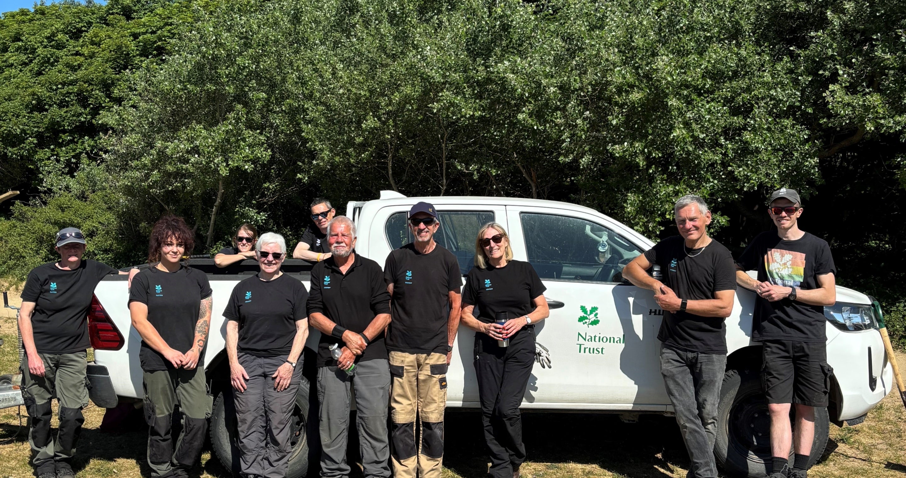 Volunteers and rangers looking happy, standing in front of a National Trust branded white van