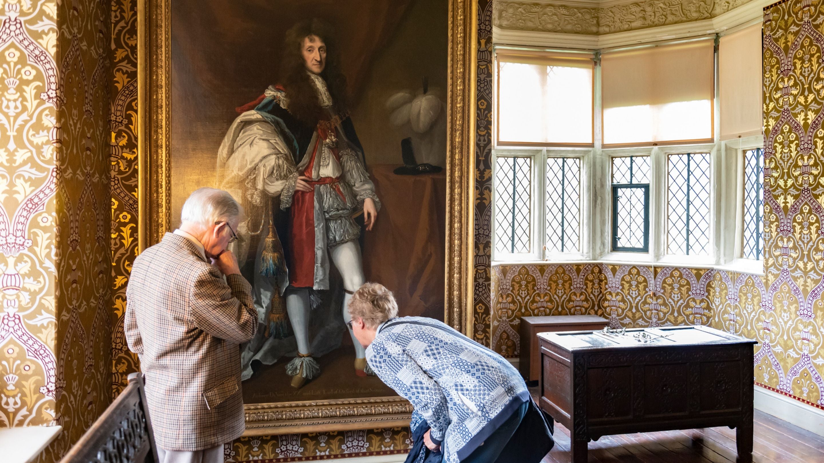 Volunteer room guide and visitor in the Long Gallery at Gawthorpe Hall, Lancashire. Portraits are on loan from the National Portrait Gallery.