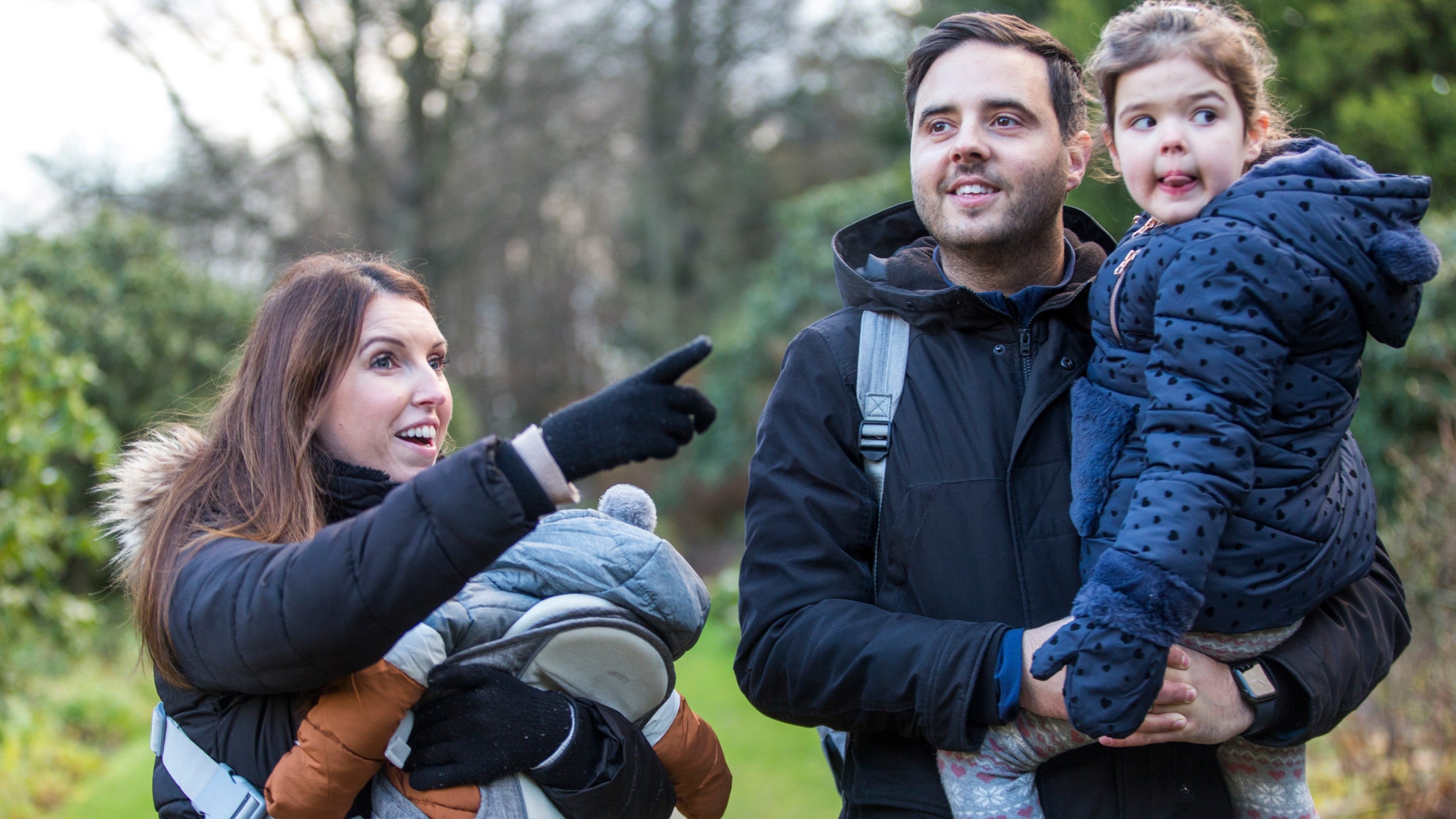 A family of two adults and two children in the garden at Rufford Old Hall. They are dressed for winter and the woman is pointing at something out of frame.