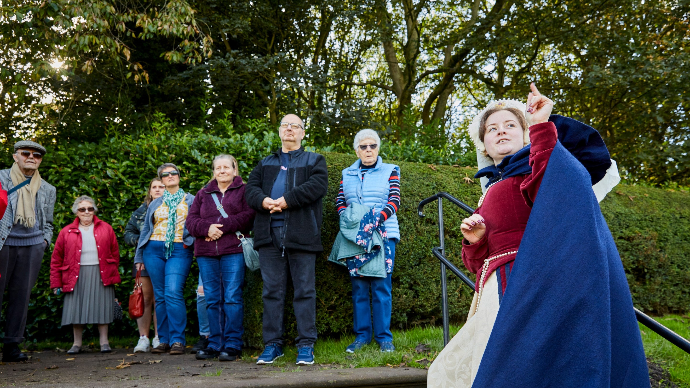 A costumed volunteer points at something out of shot in front of a group of visitors at Speke Hall, Liverpool