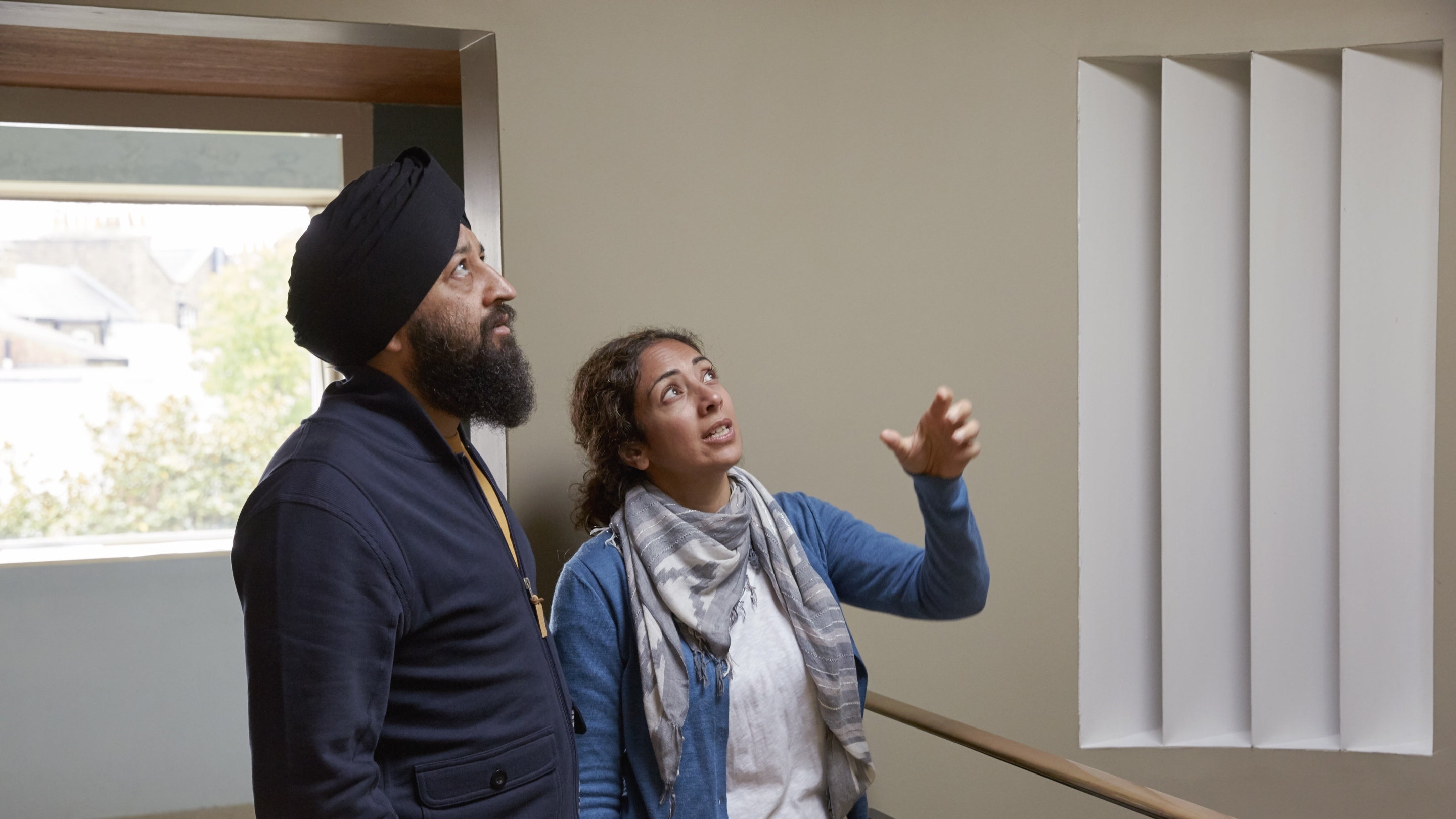 Two visitors looking up at the ceiling in a white room at 2 Willow Road