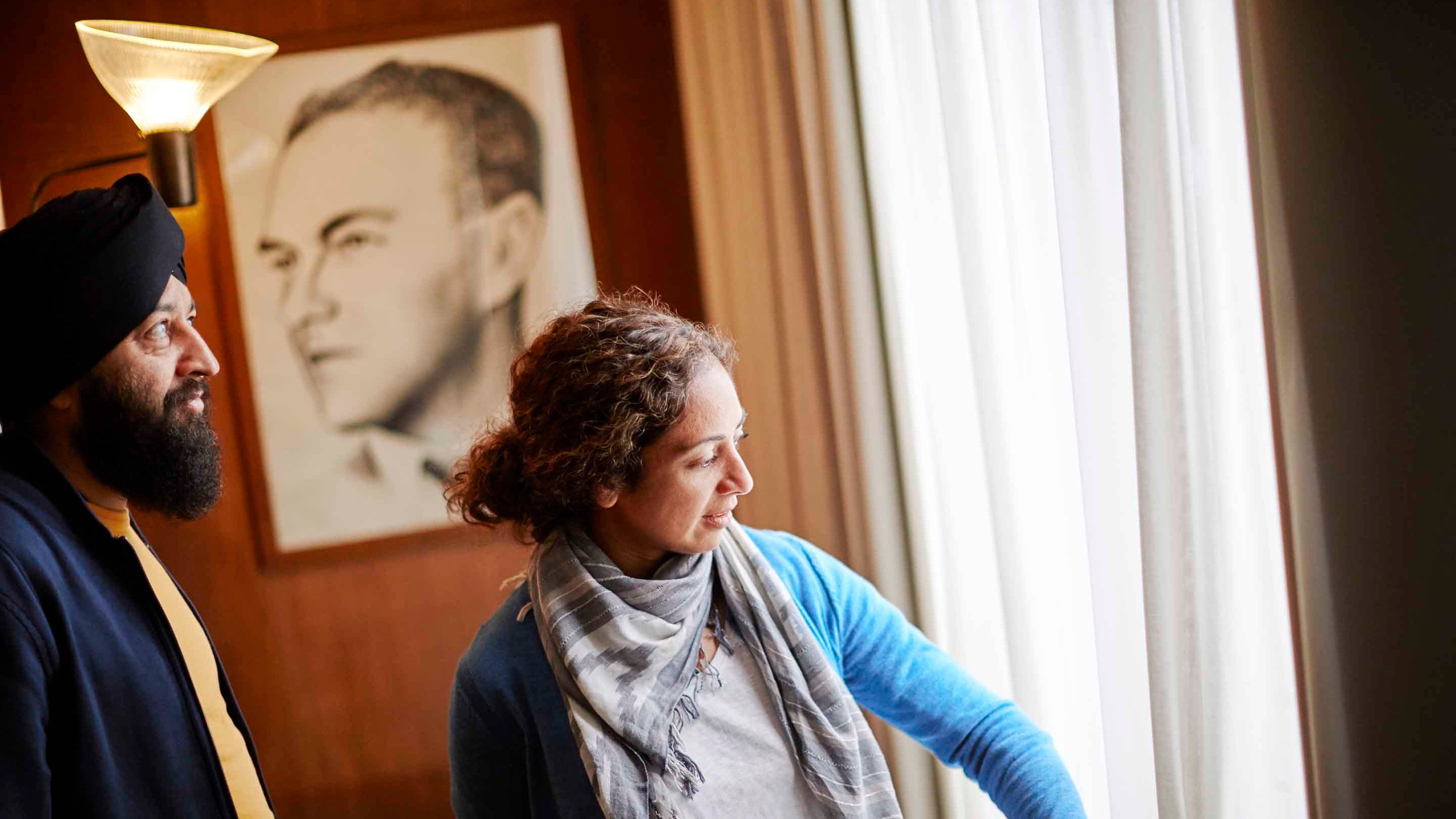 Two visitors inside 2 Willow Road, moving aside a curtain to look out of a window