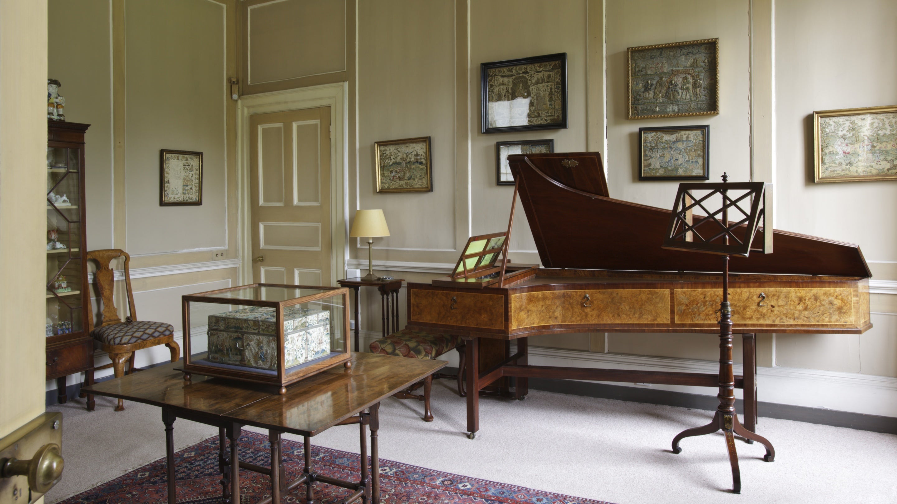 An antique keyboard instrument, and a music stand, with a display case, in the music room at Fenton House and Garden, London