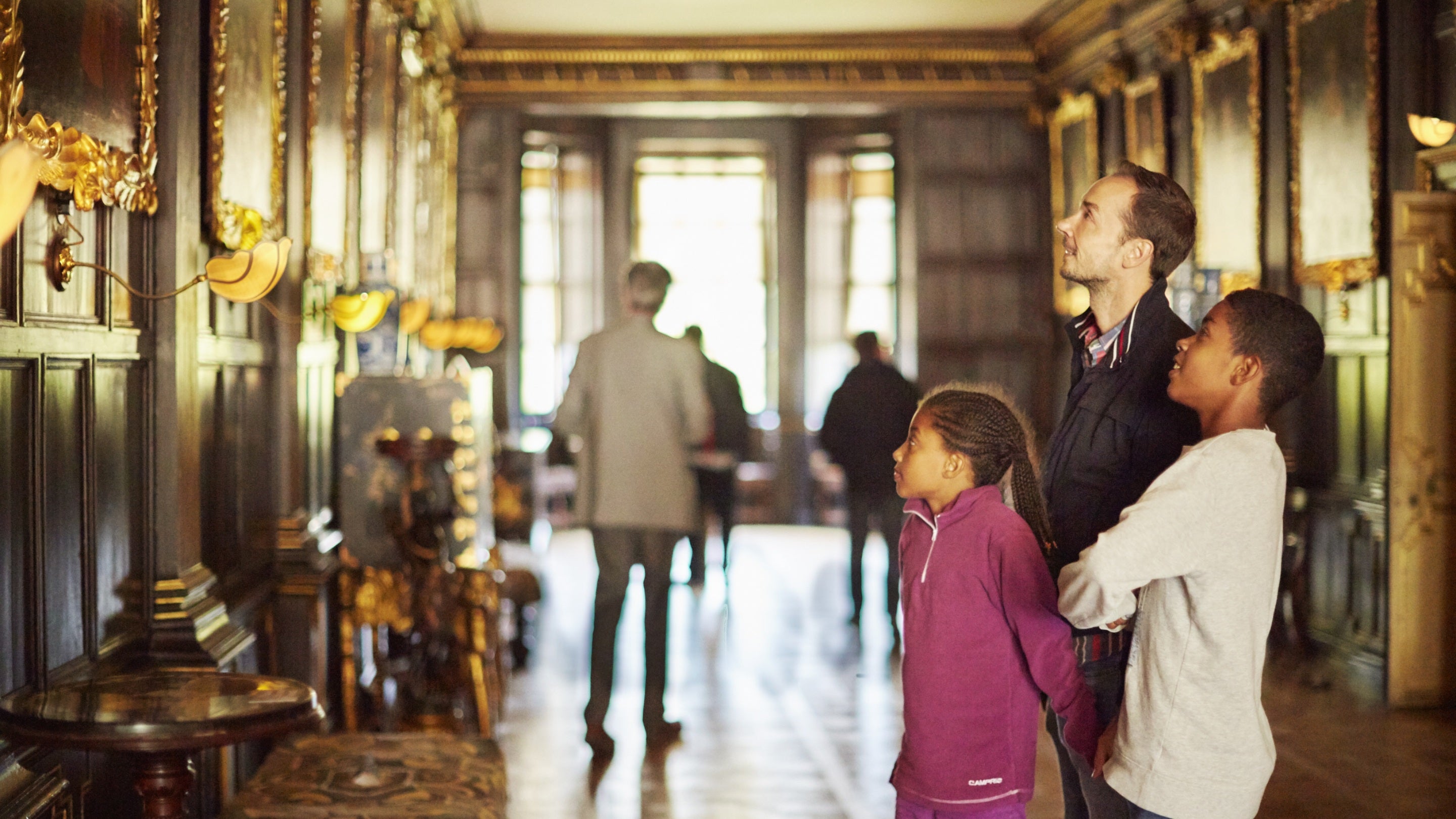 A family looking at paintings in the Long Gallery at Ham House and Garden, Surrey