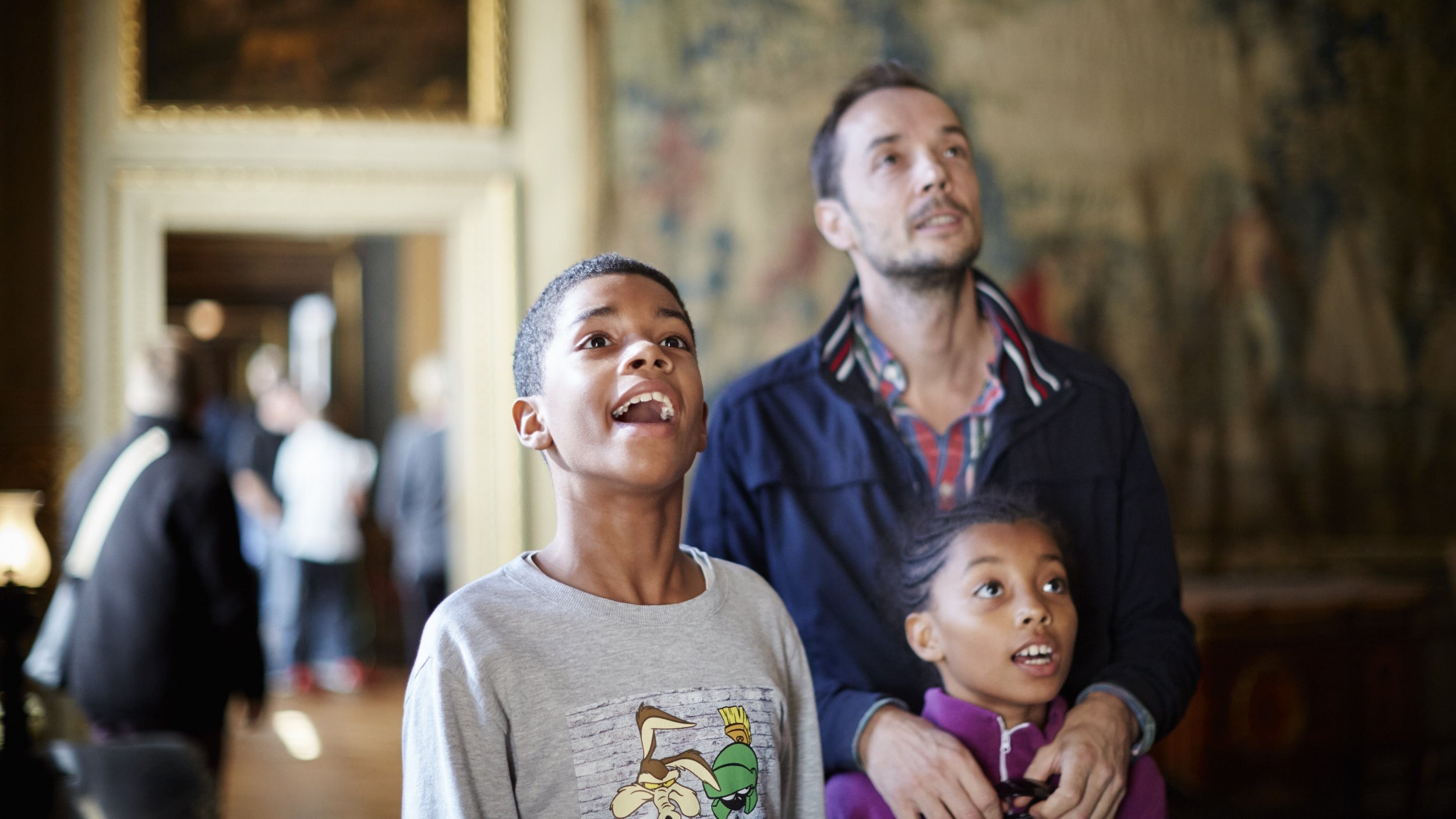 Father and two children looking up in wonder at display in Ham House
