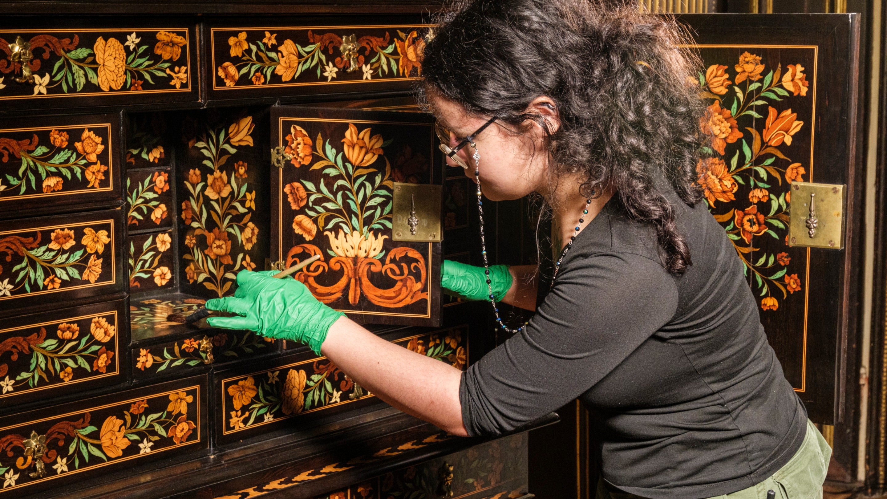 Cleaning the Gerrit Jensen cabinet in the Long Gallery at Ham House and Garden, Surrey