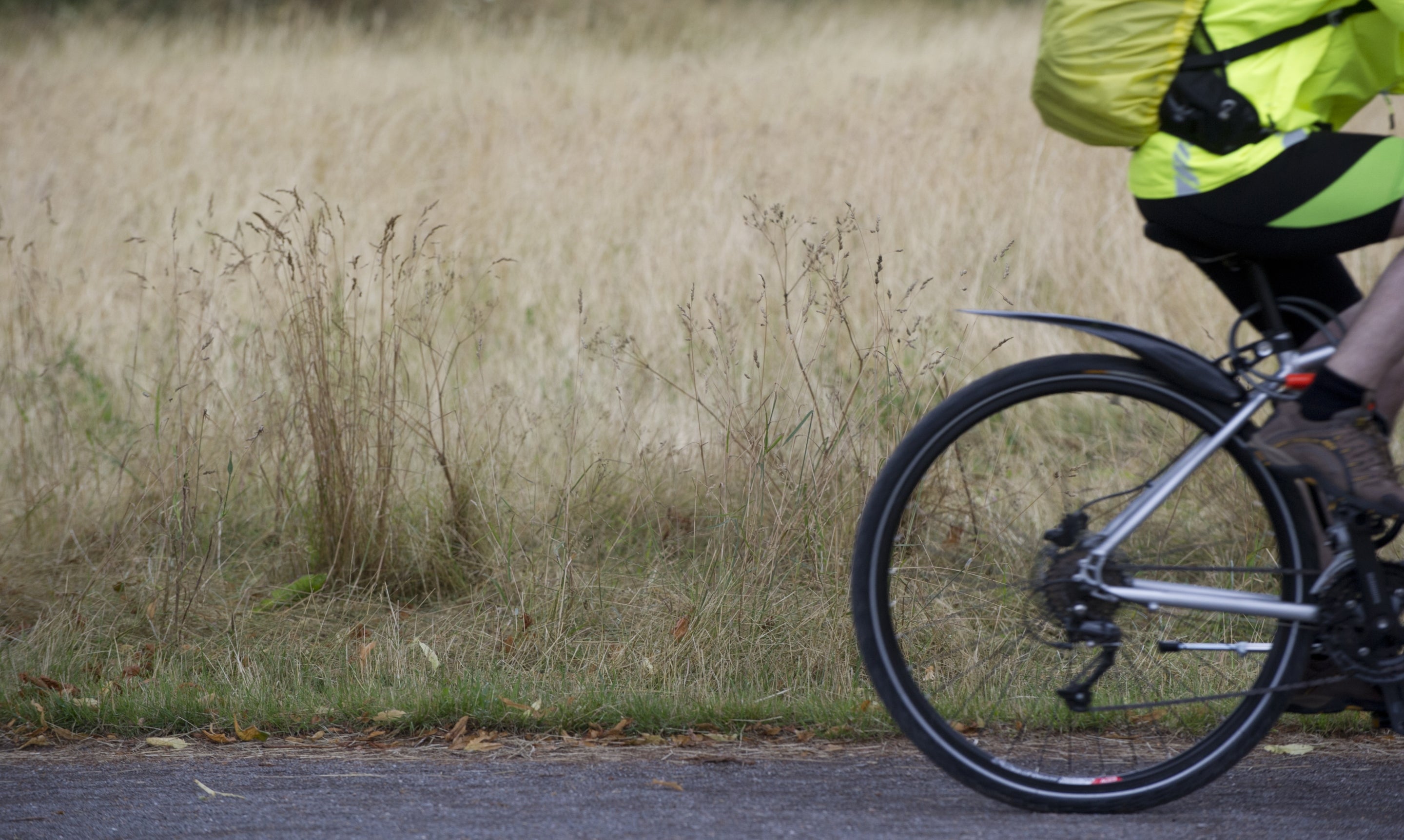 Visitor cycling along a path through Morden Hall Park, London.