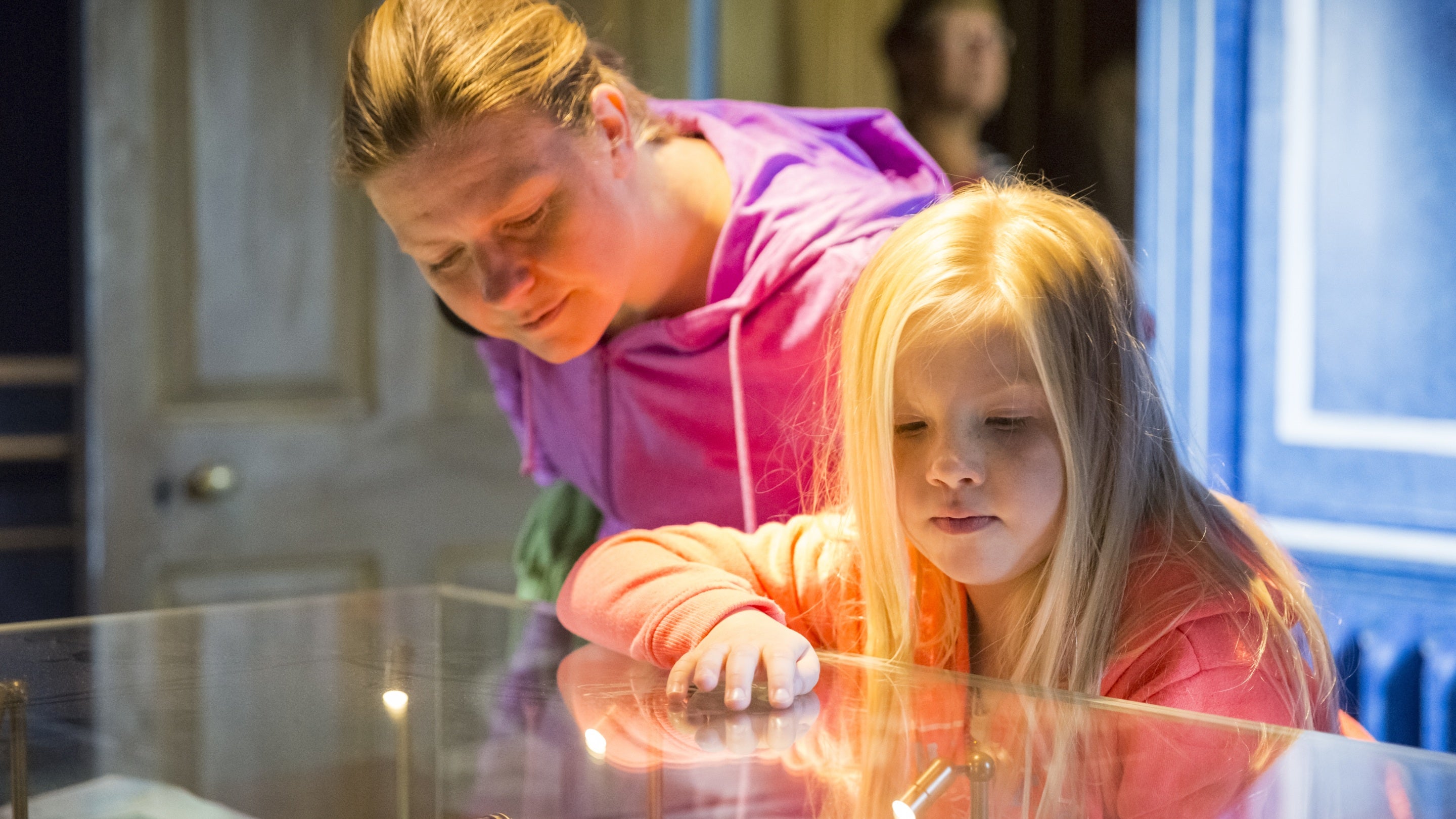 A woman and child examine the contents of a glass case at Rainham Hall, London