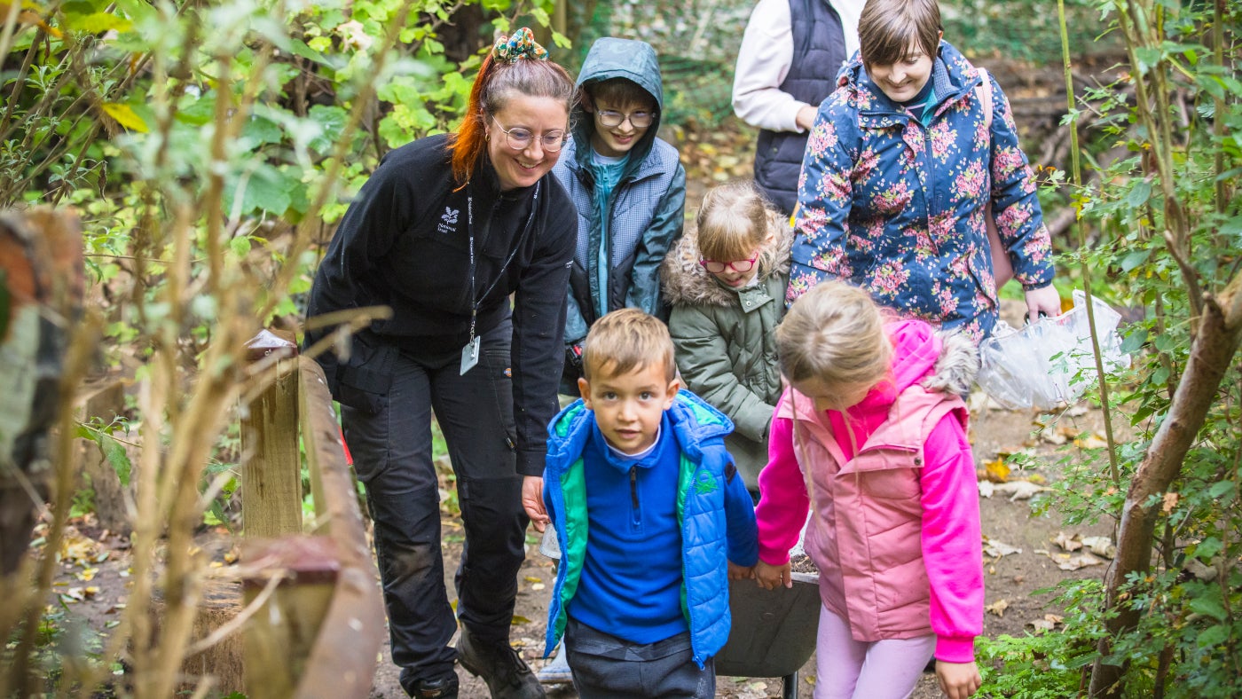 A group of young rangers at Rainham Hall,  all helping to push a wheelbarrow