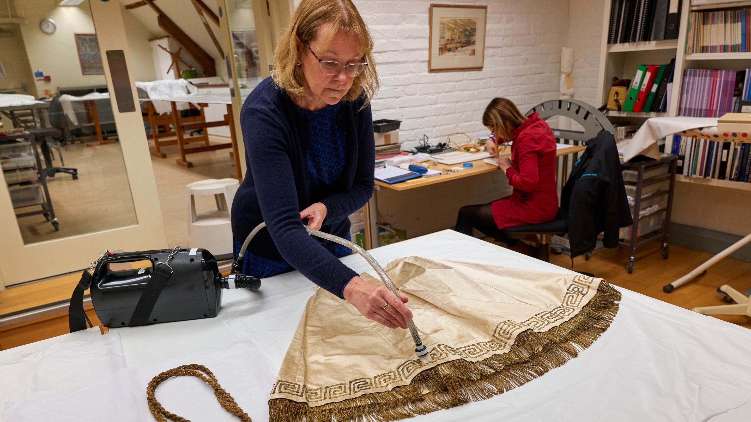 A conservator cleaning fabric at the Textile Conservation Studio at Blickling, Norfolk