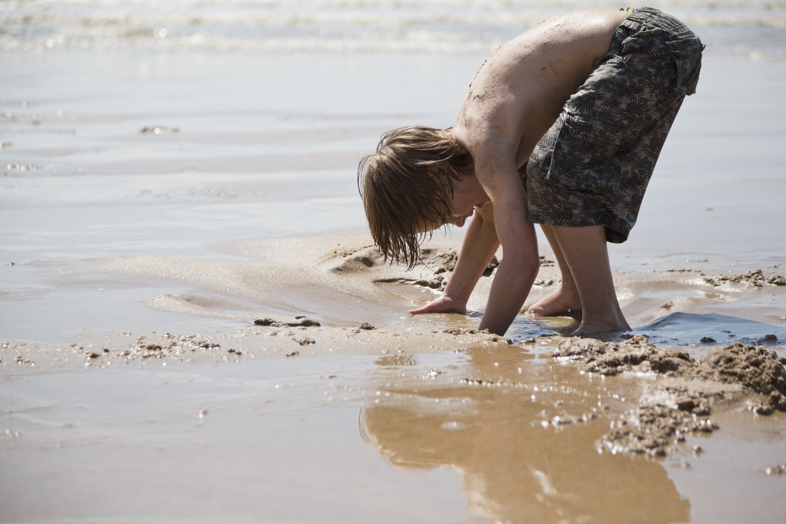 A child plays barefoot in the sand on the beach