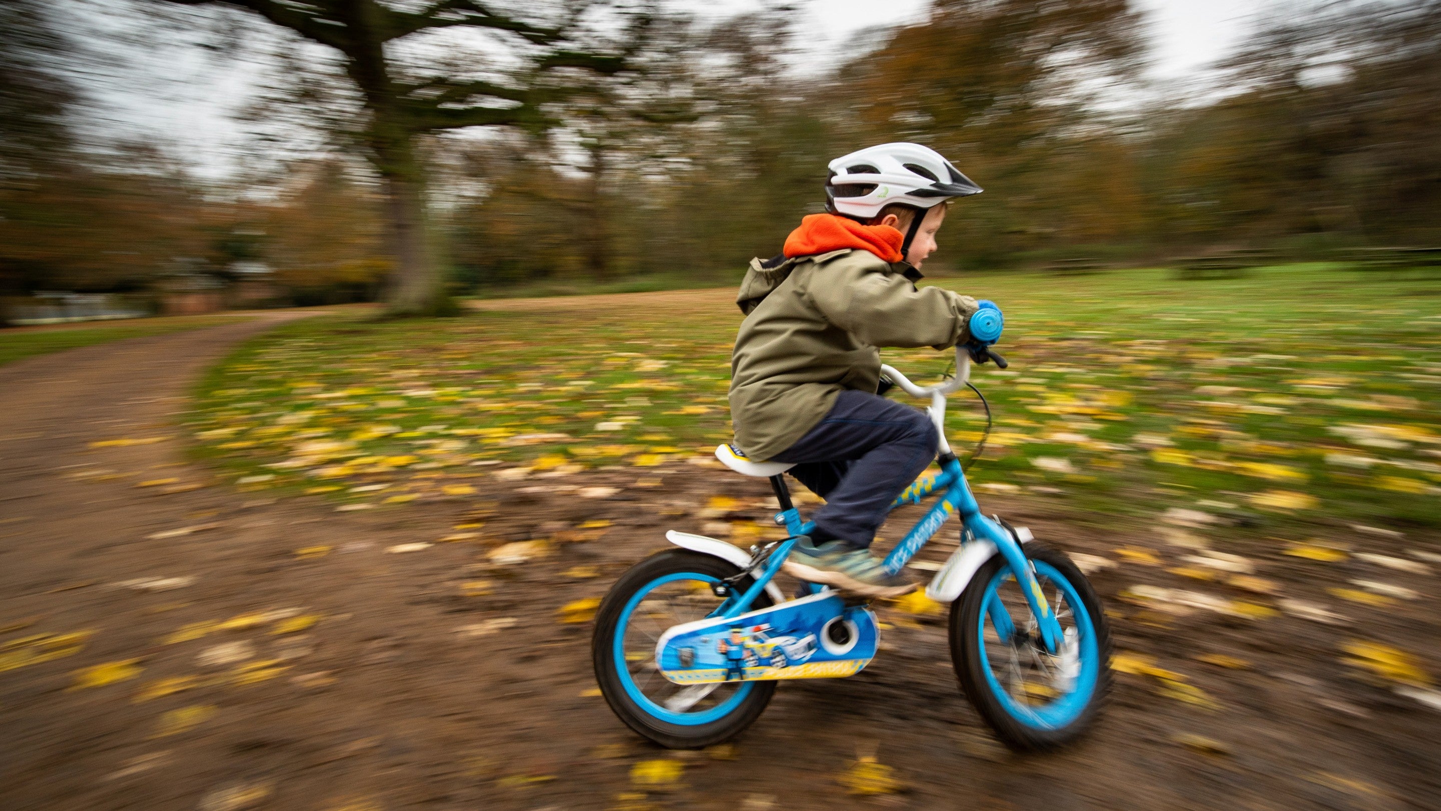 Child riding bike through autumn leaves at Felbrigg