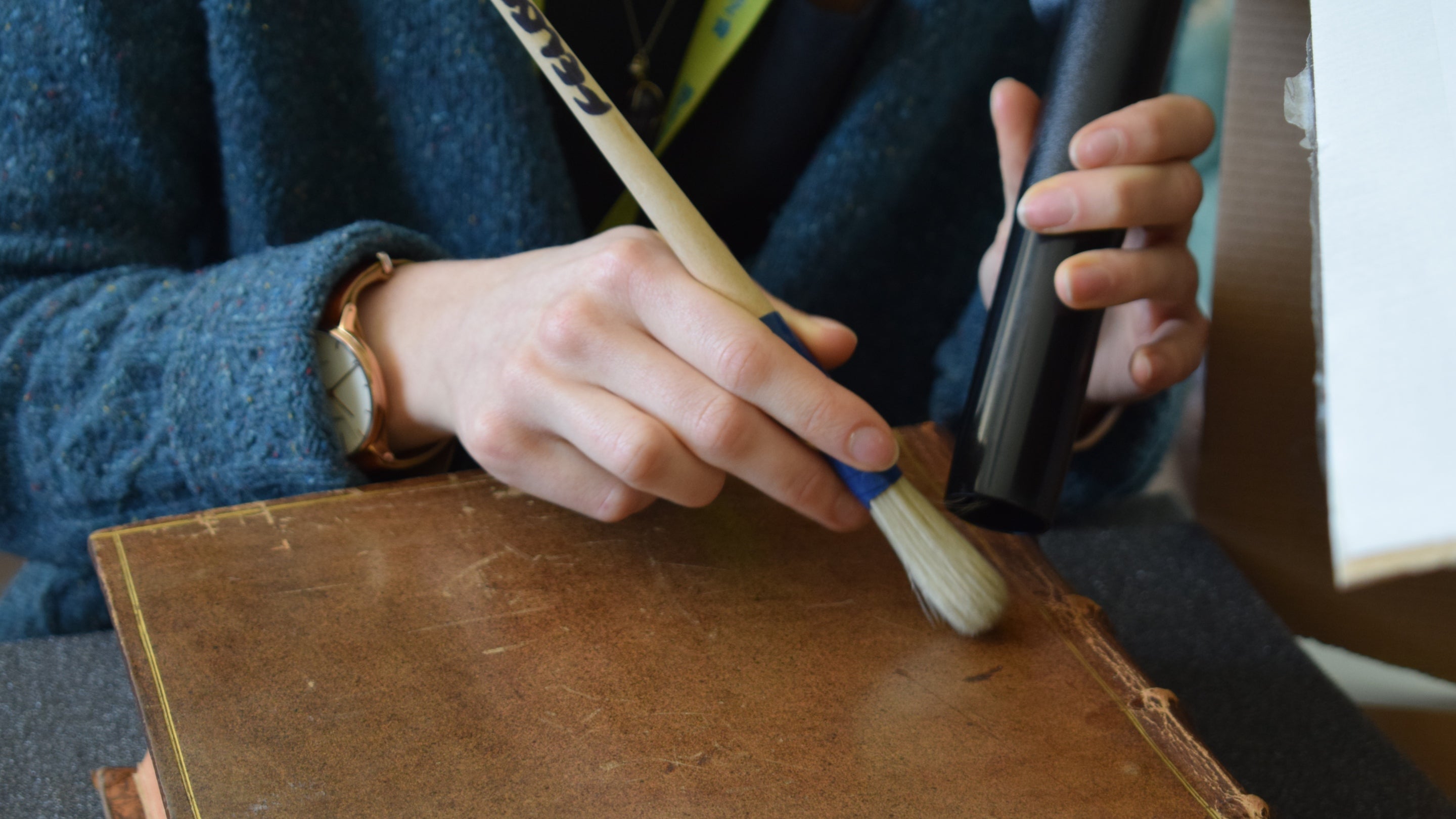 A close up of a conservation assistant undertaking mould cleaning on a book with a brush at Felbrigg Hall, Norfolk