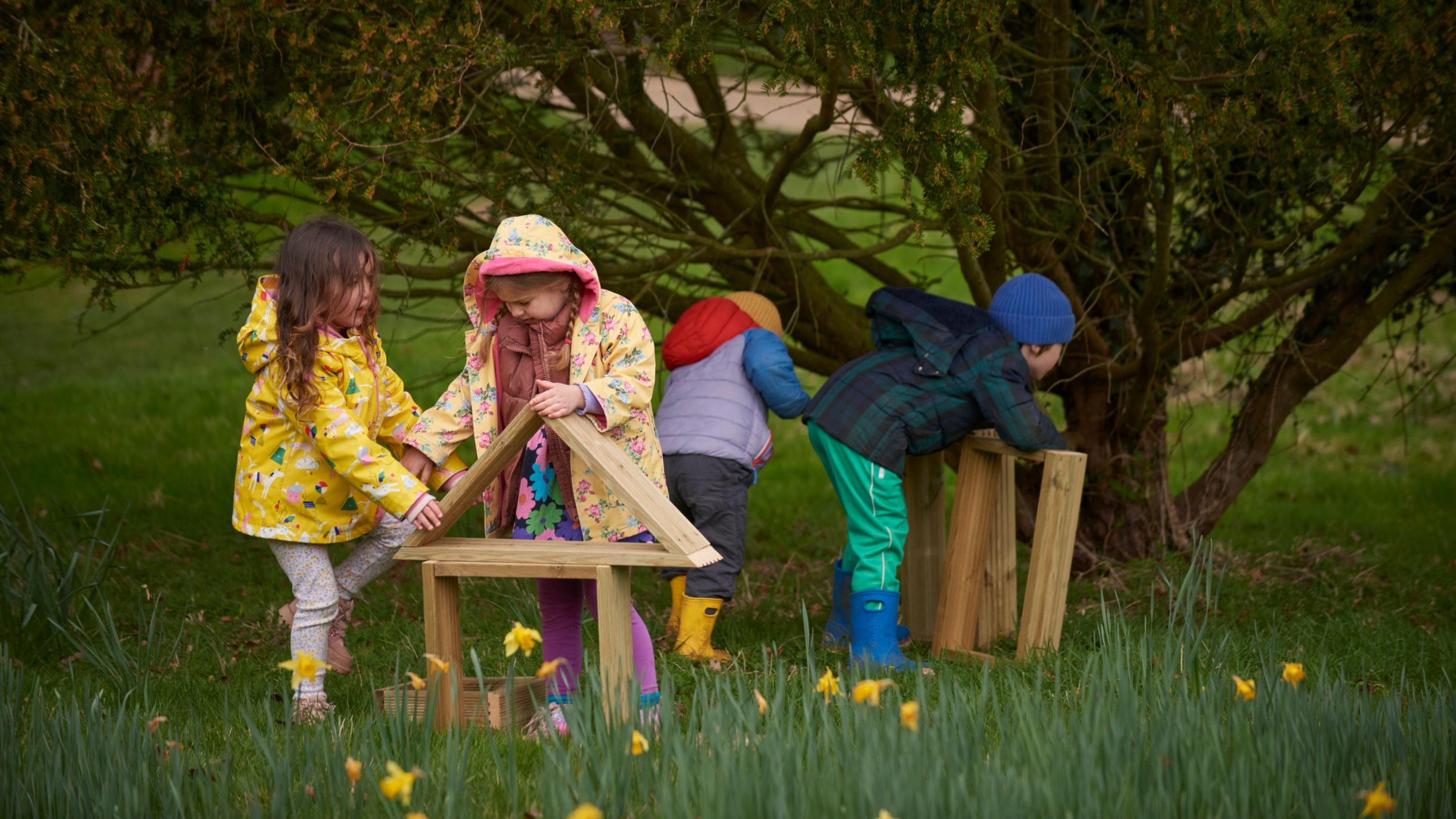 Children in colourful coats play with giant building blocks among the daffodils on the Felbrigg Estate