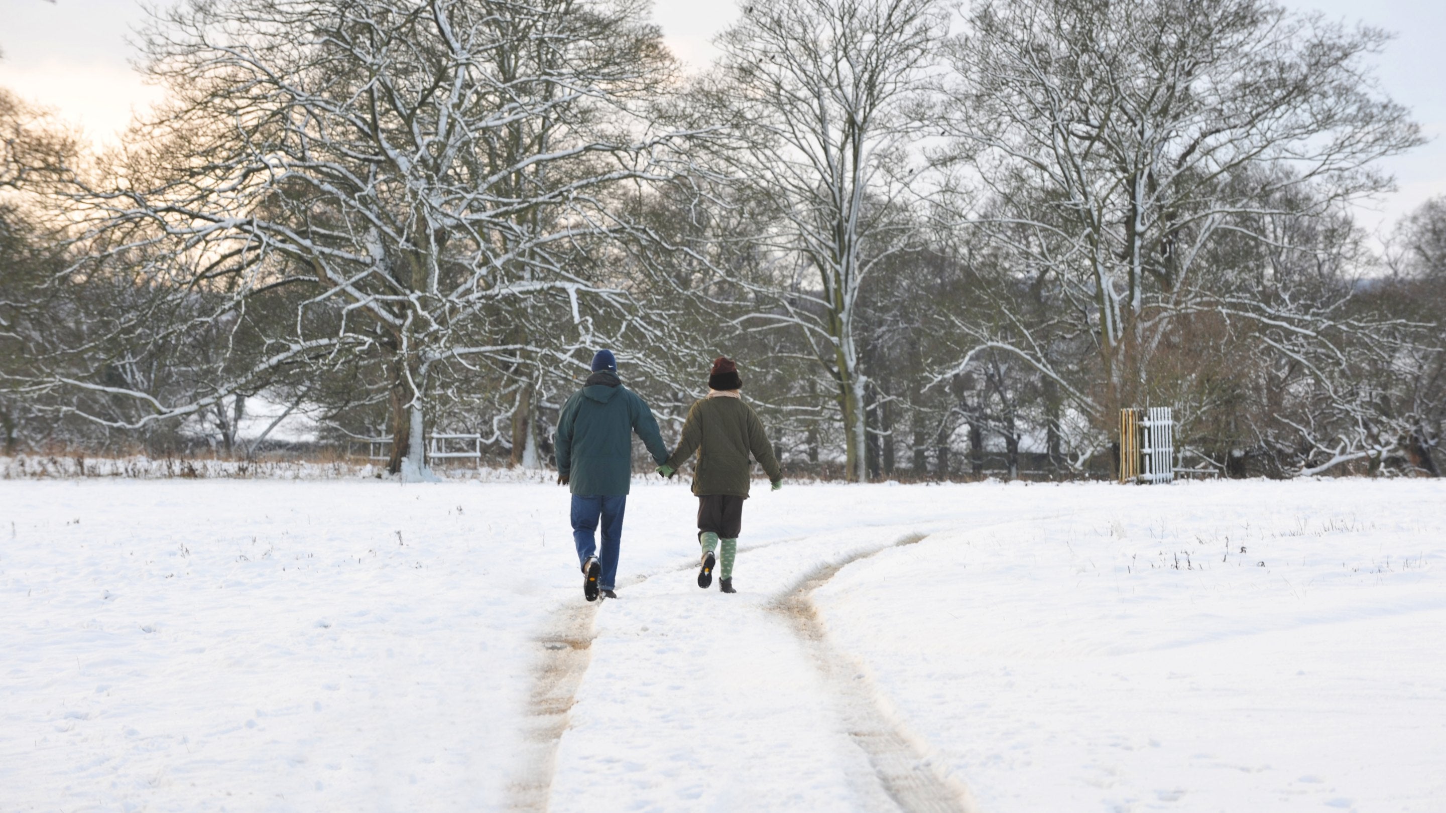 Visitors enjoy a winter walk across snow-covered grounds, following a path through the landscape framed by frost-covered trees.