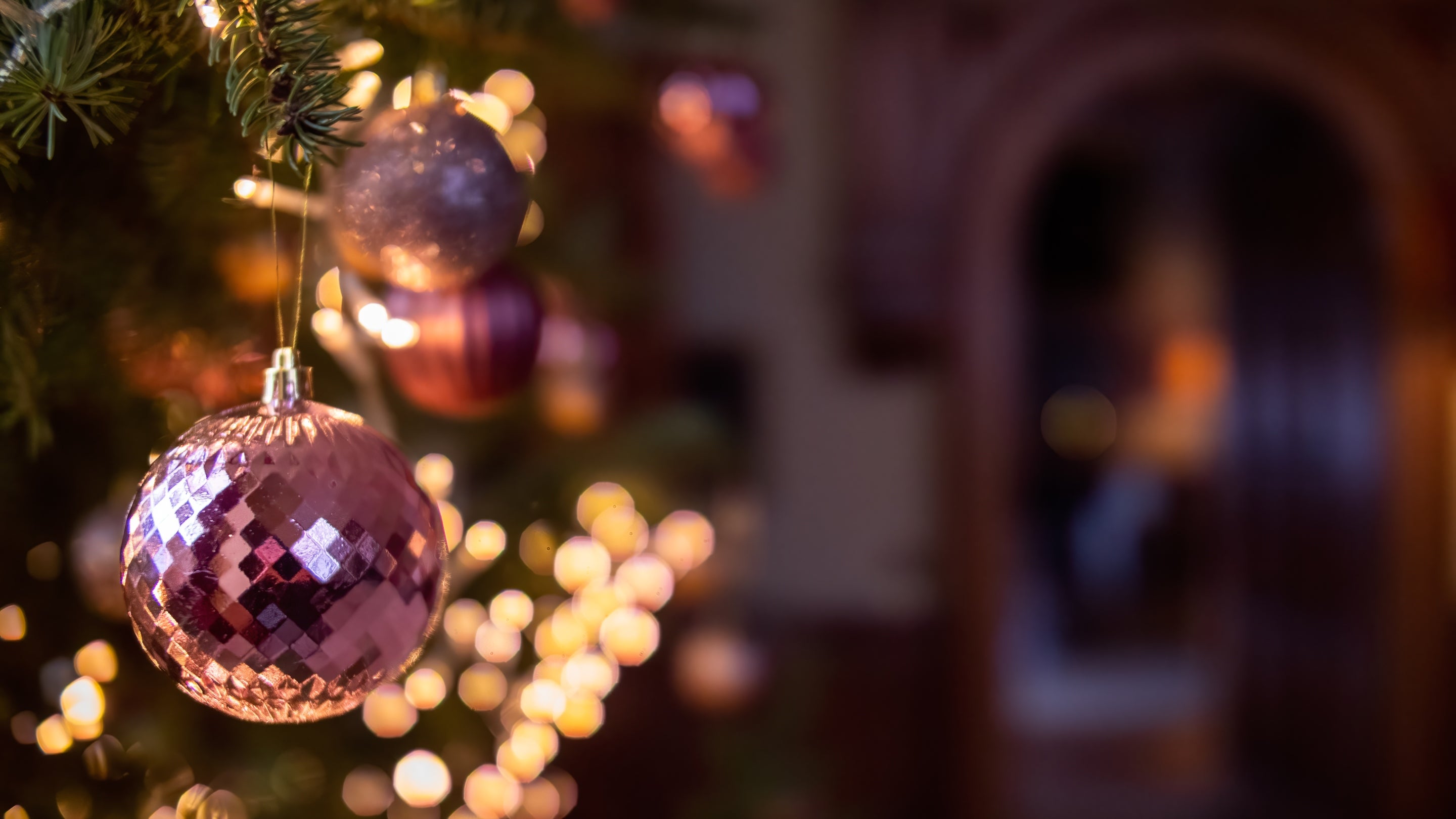 Pink and silver Christmas baubles on a tree, glowing with warm lights inside Felbrigg Hall