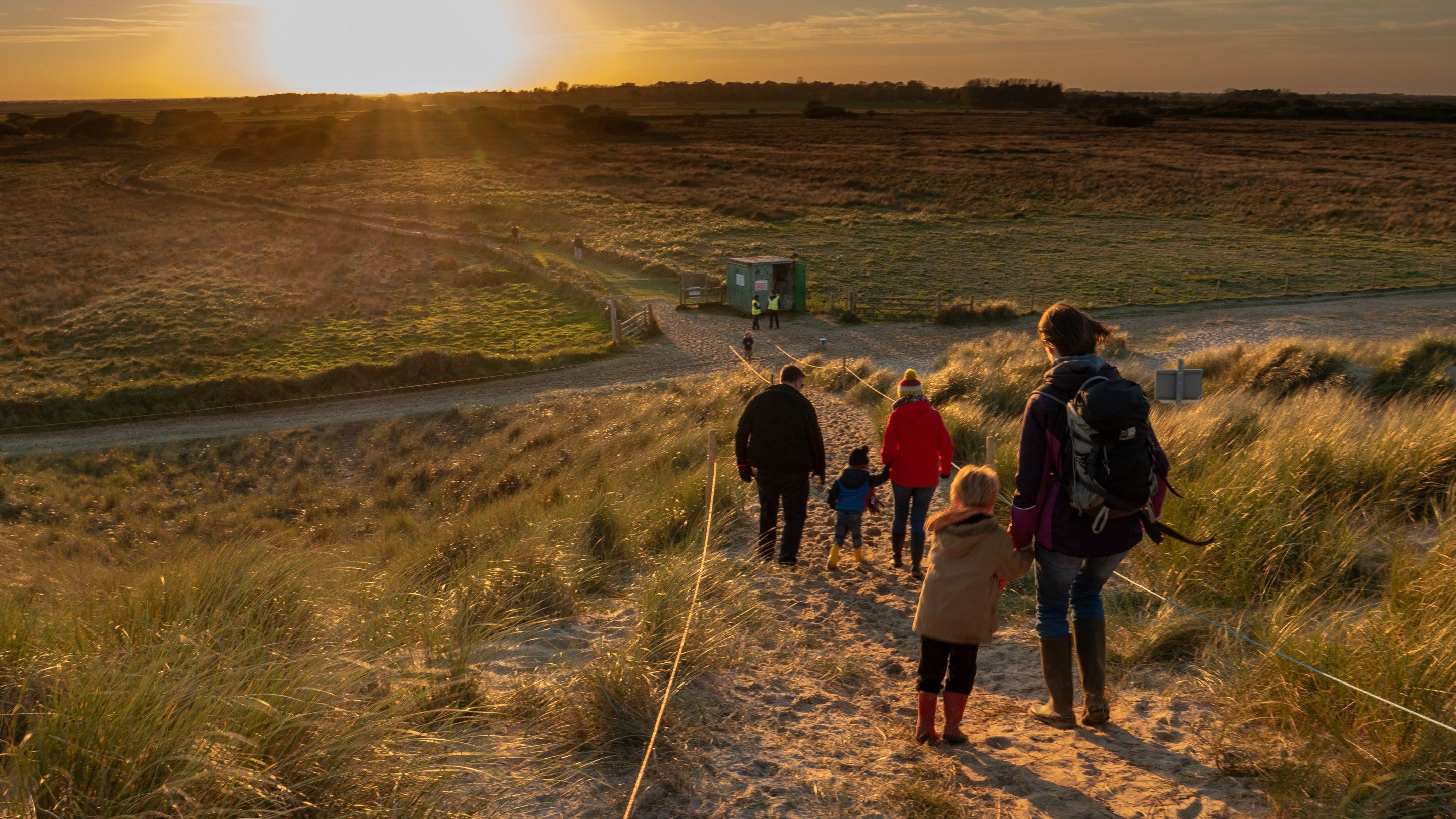 Family descend down dune path from seal watchpoint at Horsey Windpump, Norfolk