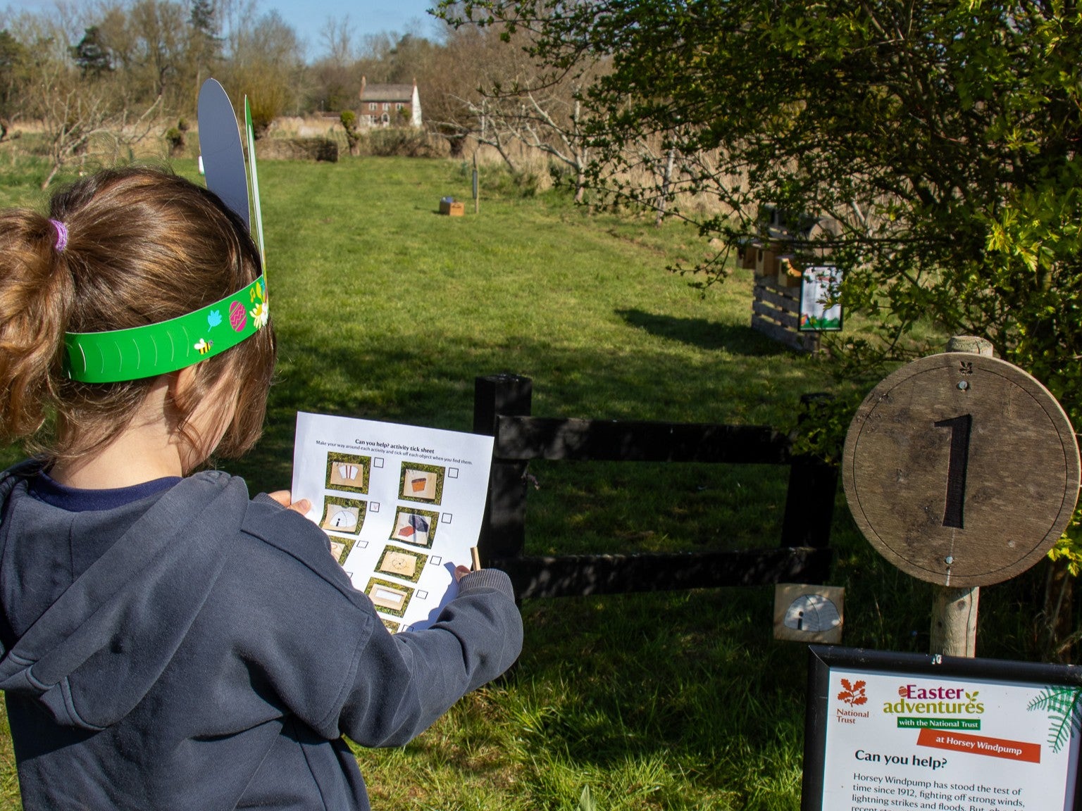 A girl wearing bunny ears following the Easter trail in the orchard at Horsey Windpump