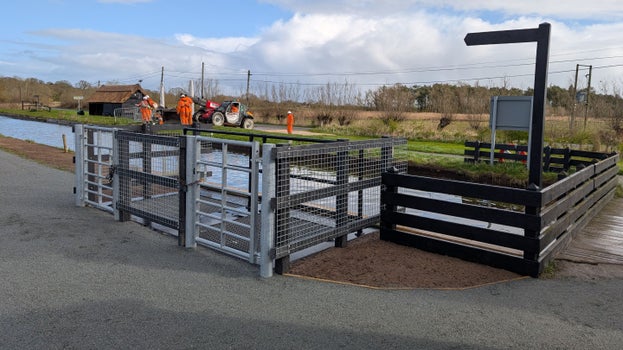A view of the footpath path crossing the staithe in front of the windpump, with a signpost showing the direction to the viewpoint.