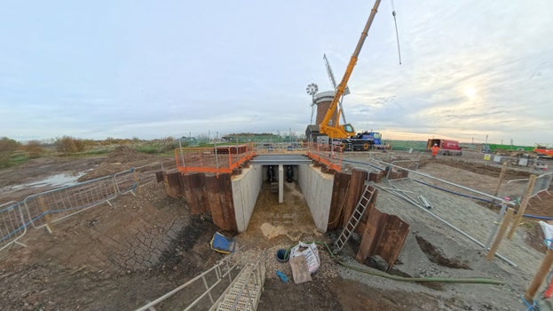 In the foreground is the wet well concrete structure that sits below ground level and beyond is a tall crane next to Horsey Windpump