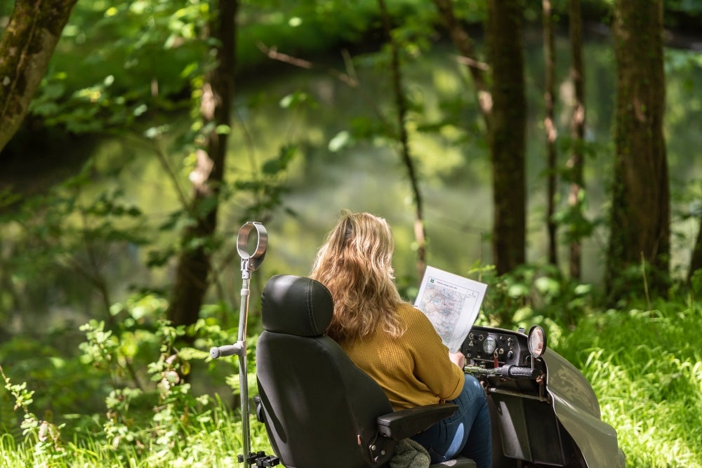 A female visitor uses a National Trust PMV to explore the accessible pathways at Woolacombe in Devon.