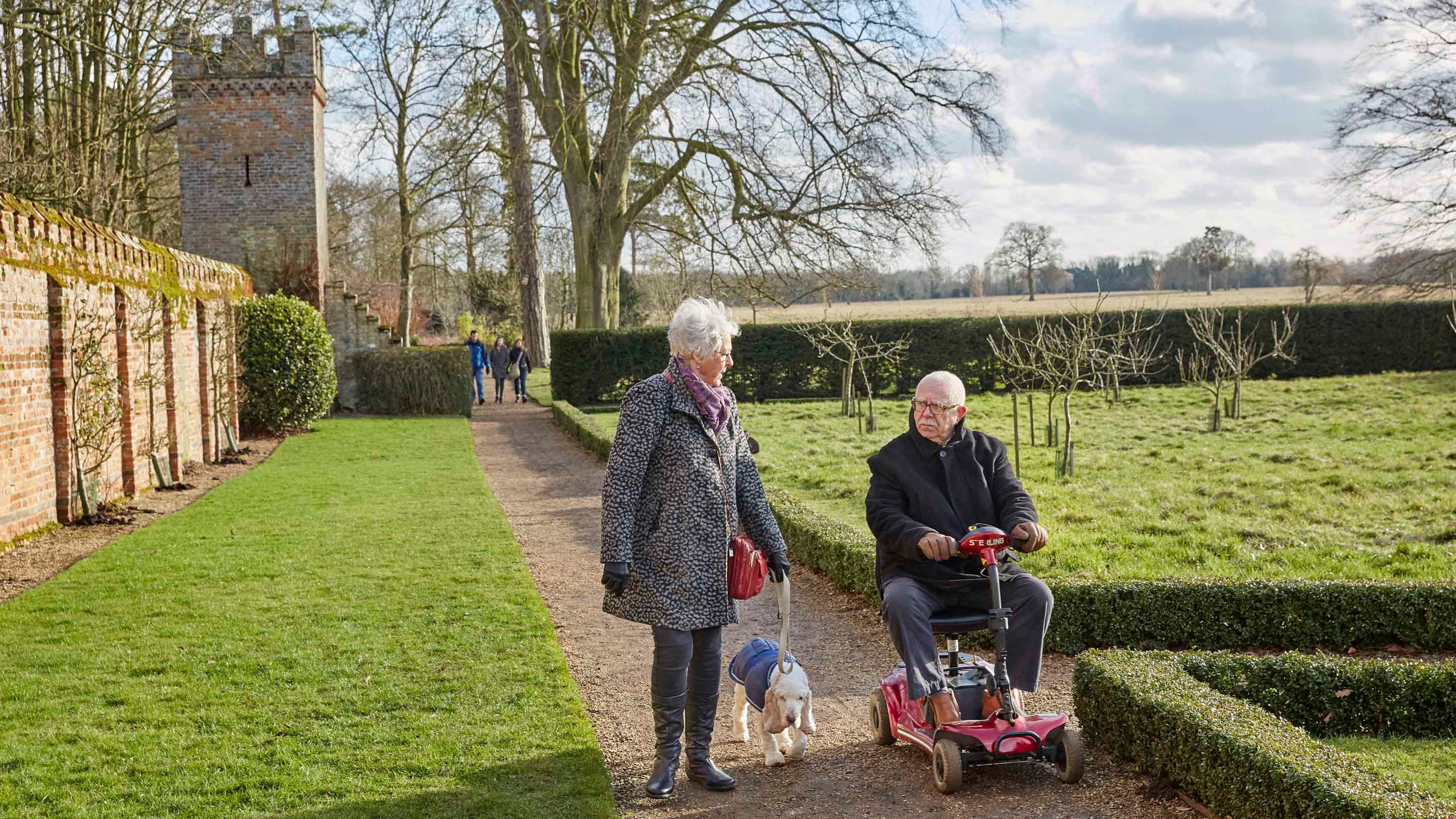 Visitors exploring the grounds with their dog at Oxburgh Hall, Norfolk