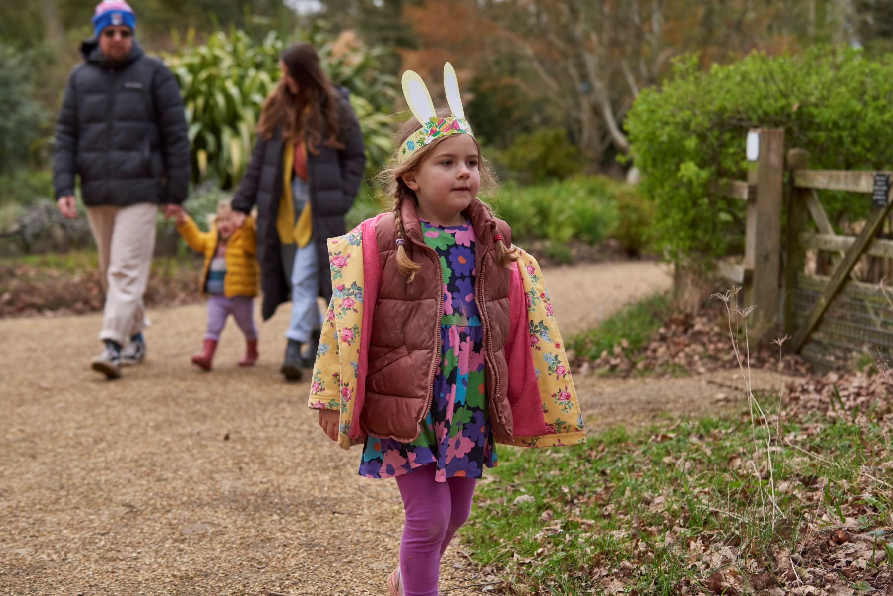 A girl wearing Easter bunny ears and her family walking along a path at Sheringham Park