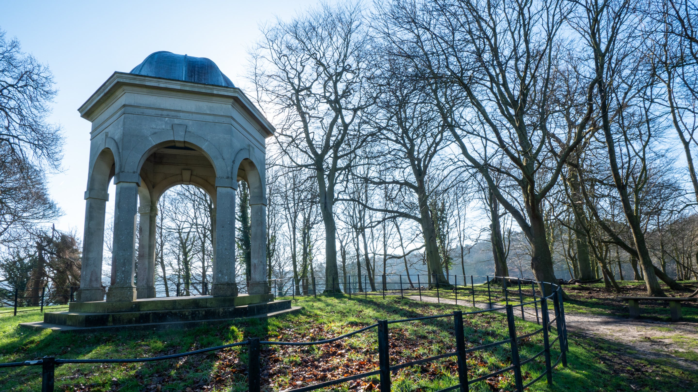 View of temple with bare trees and bright blue sky at Sheringham Park, Norfolk.