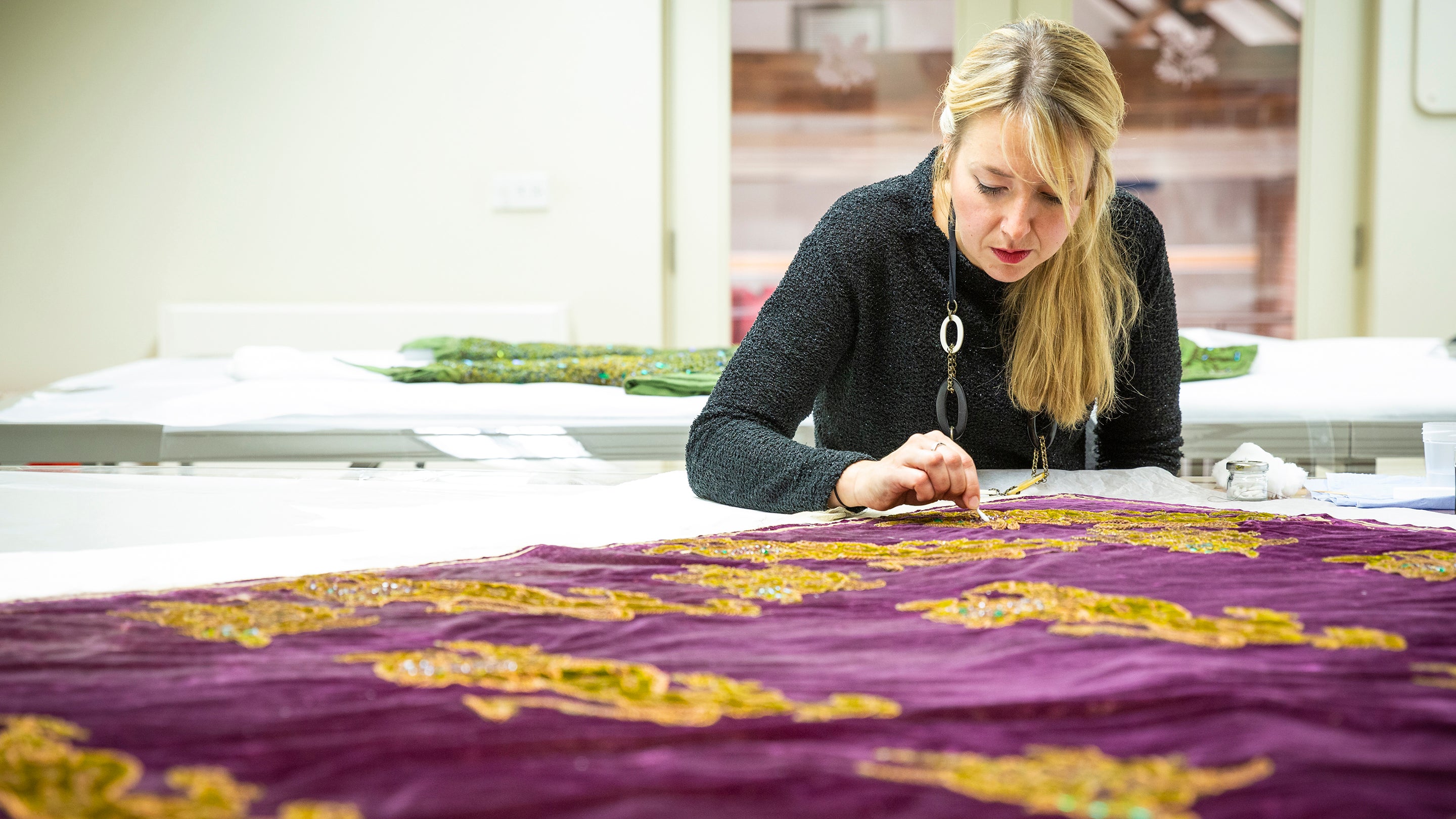 Textile Conservator stitching velvet cloak from Smallhythe Place, Kent