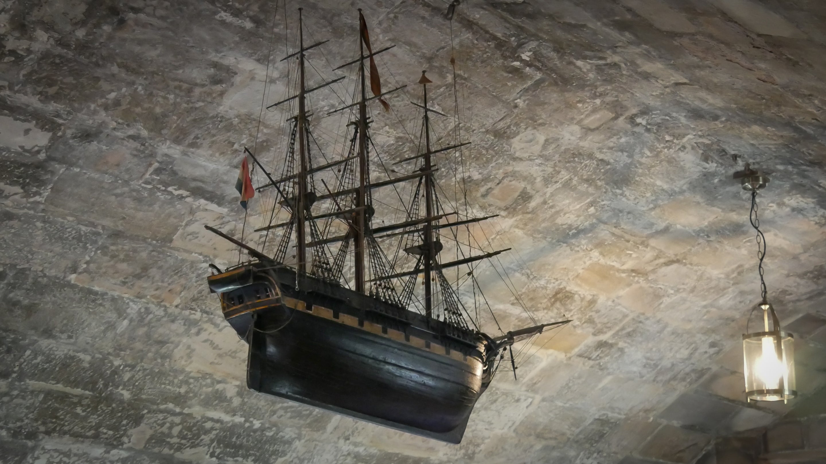 A close up of a model of a ship hanging from the ceiling in the ship room at Lindisfarne Castle.