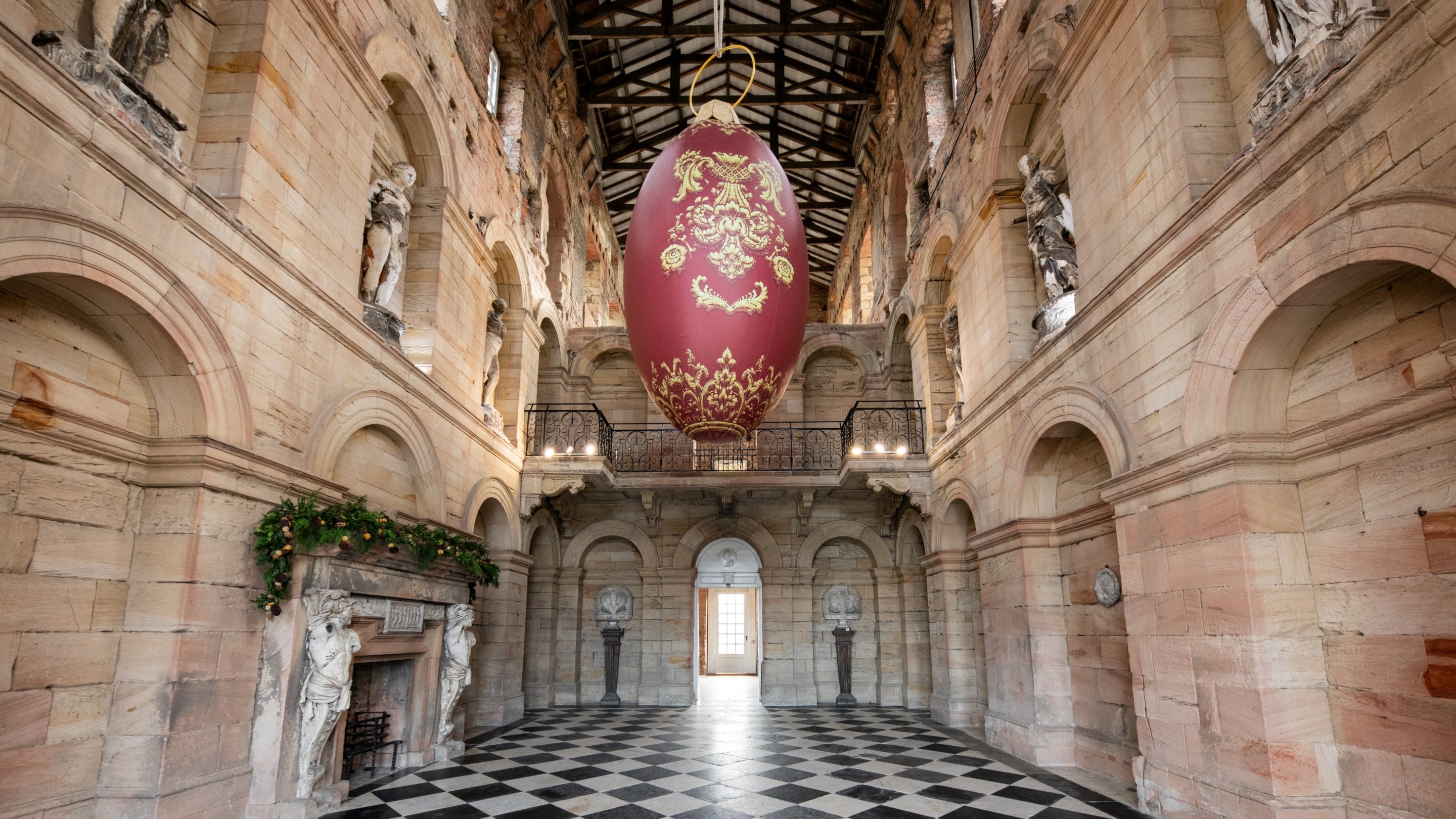 Giant red bauble suspended from the ceiling in the entrance hall at Seaton Delaval Hall