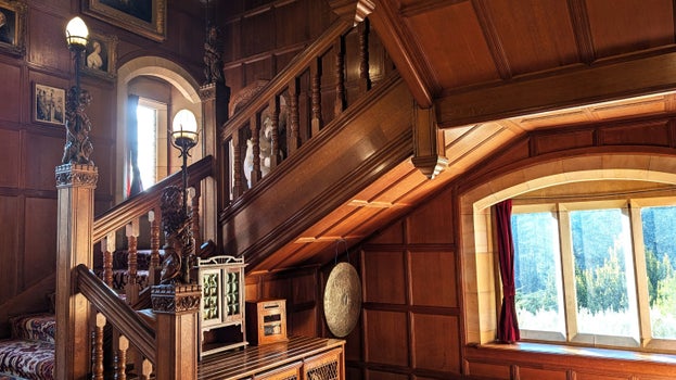 The decorative mains stairs inside Cragside House with carved lions holding torch-like lamps.