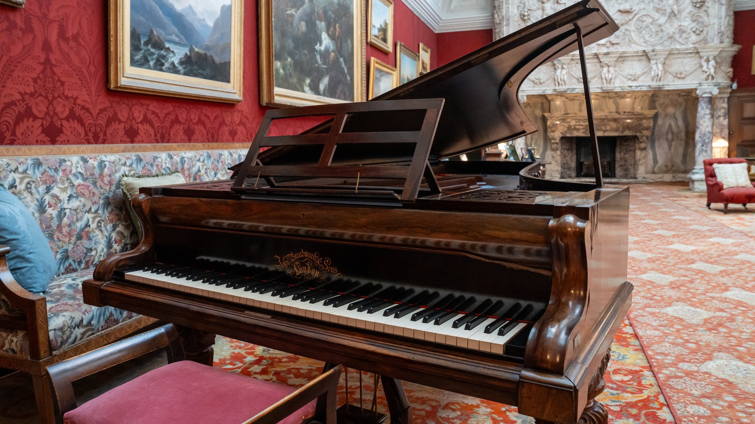 The Broadwood grand piano on display in the Drawing Room at Cragside House. The piano is presented for playing. The keys are showing, the stand has been propped and the lid is up.