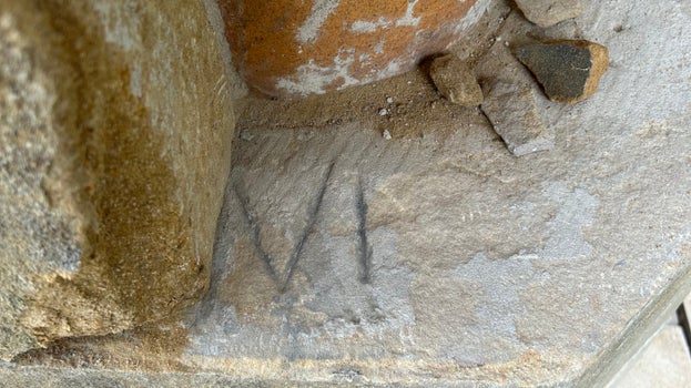 Close-up of a weathered stone surface within one of Cragside's chimneys, showing a roman number mark “VI” etched into the stone.