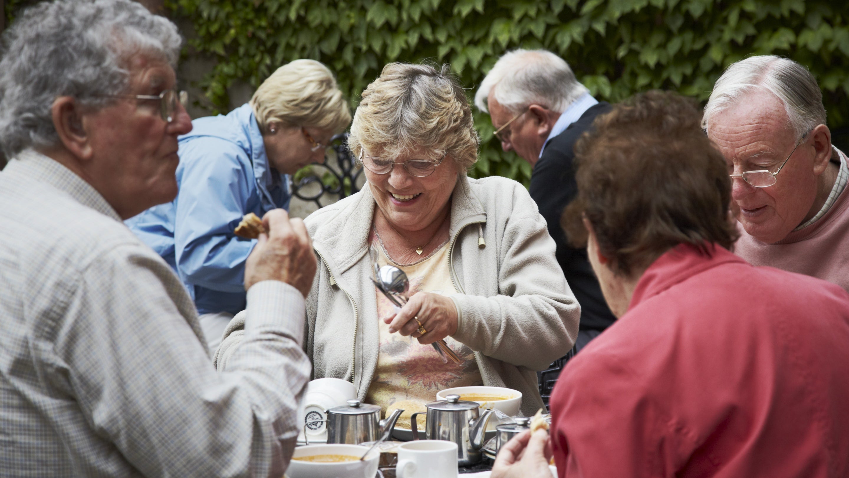 A group of visitors eating lunch outside the café at Cragside, Northumberland.