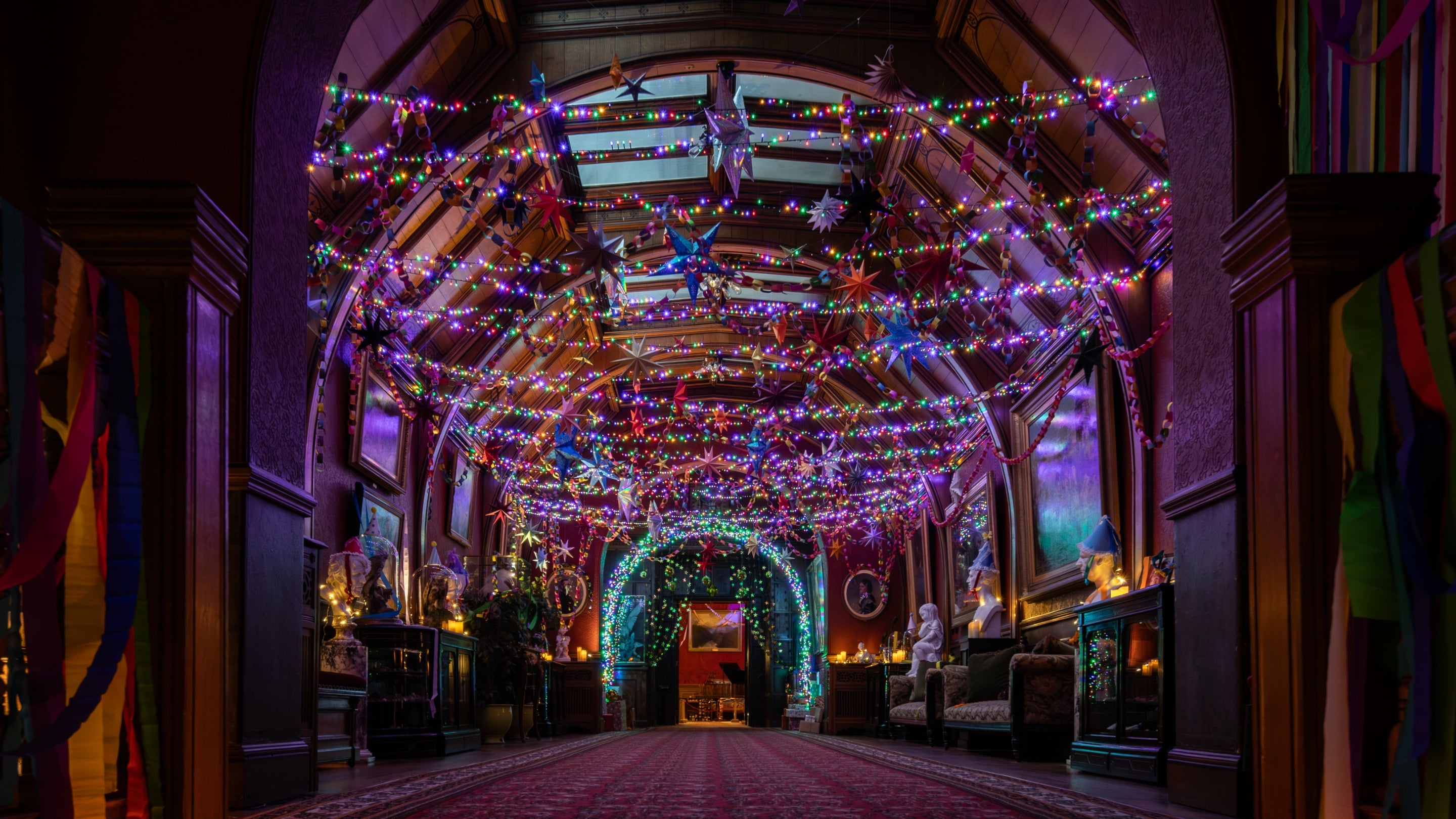 The Gallery at Cragside House decorated in swathes of colourful fairy lights and hanging stars.