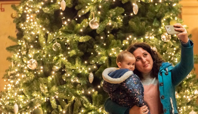 A mother and baby taking a selfie in front of a Christmas tree