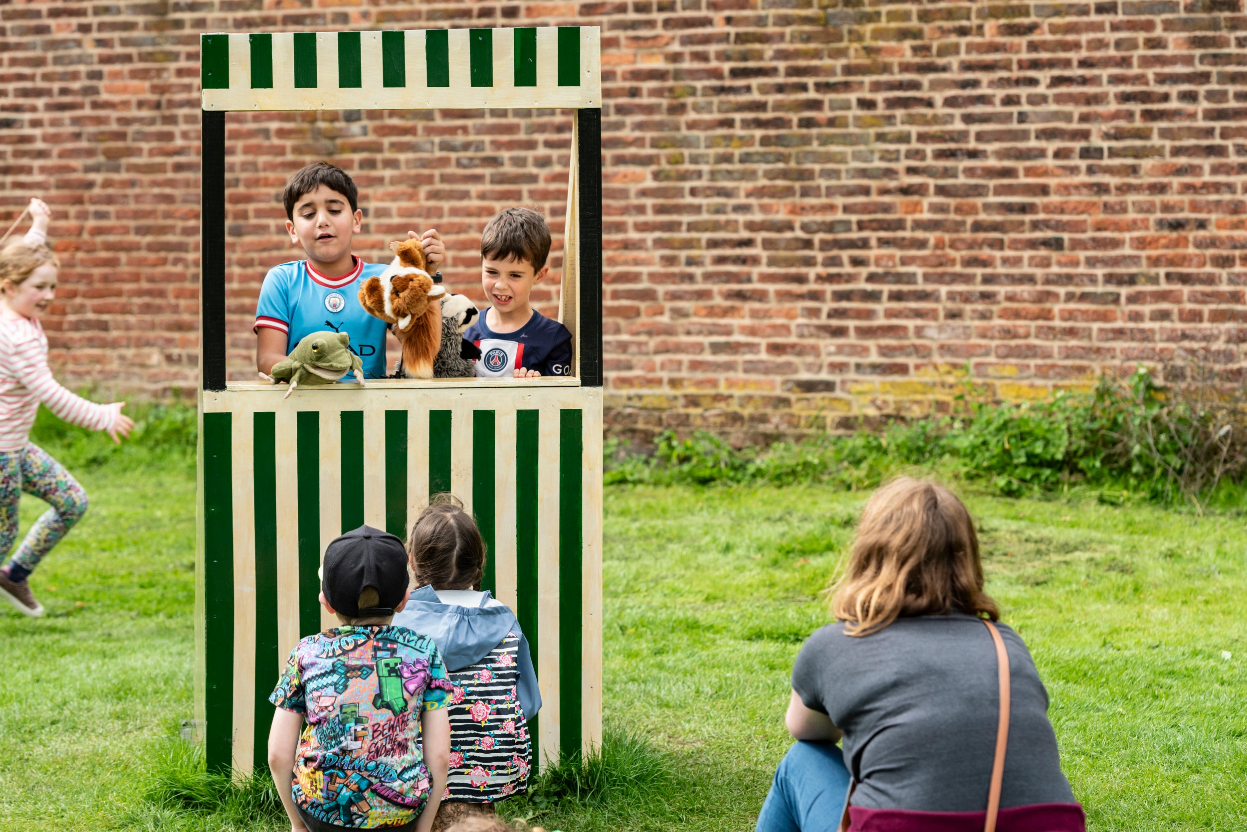 Two children put on a show in the mini stiped 'puppet theatre'.