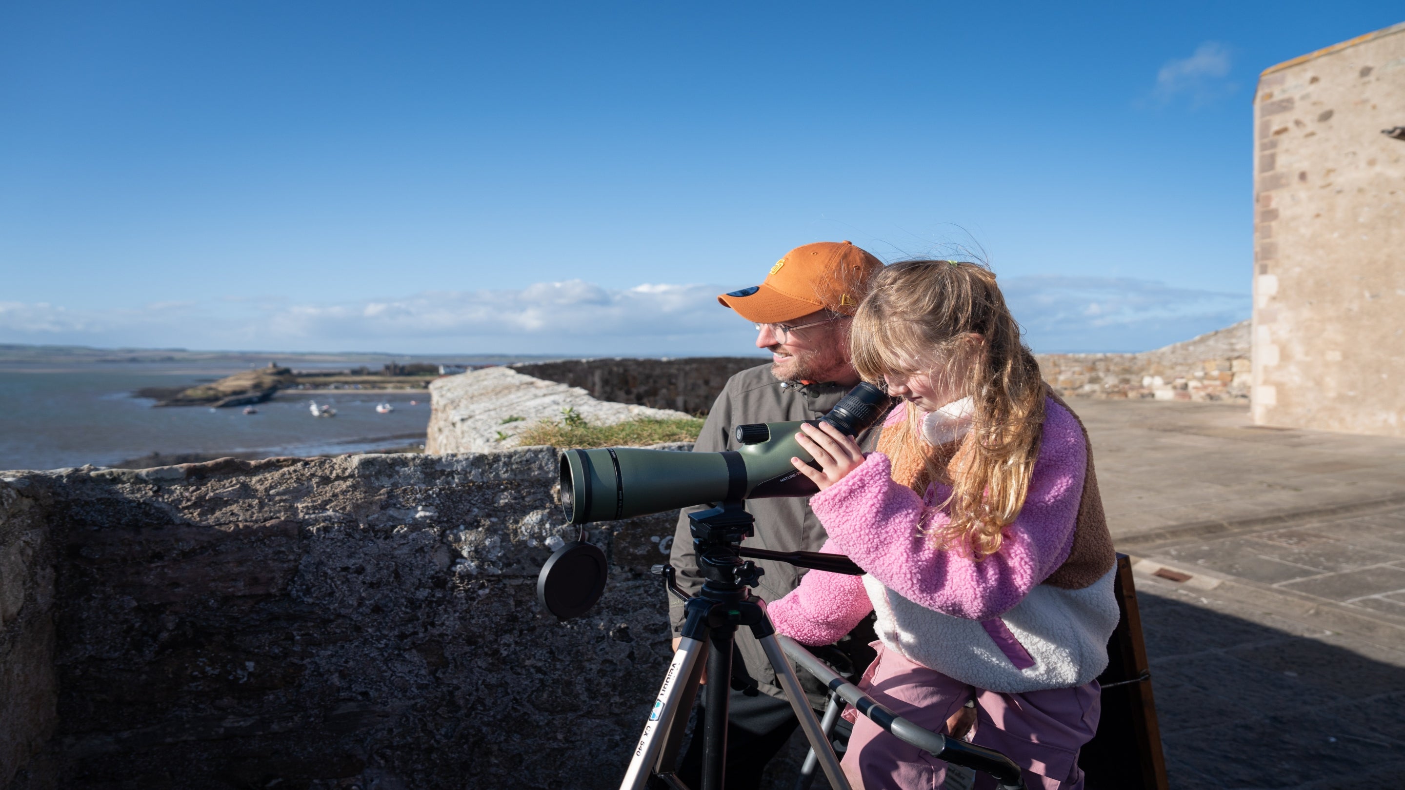 Family visitors spotting seals through a scope from the Upper Battery of Lindisfarne Castle