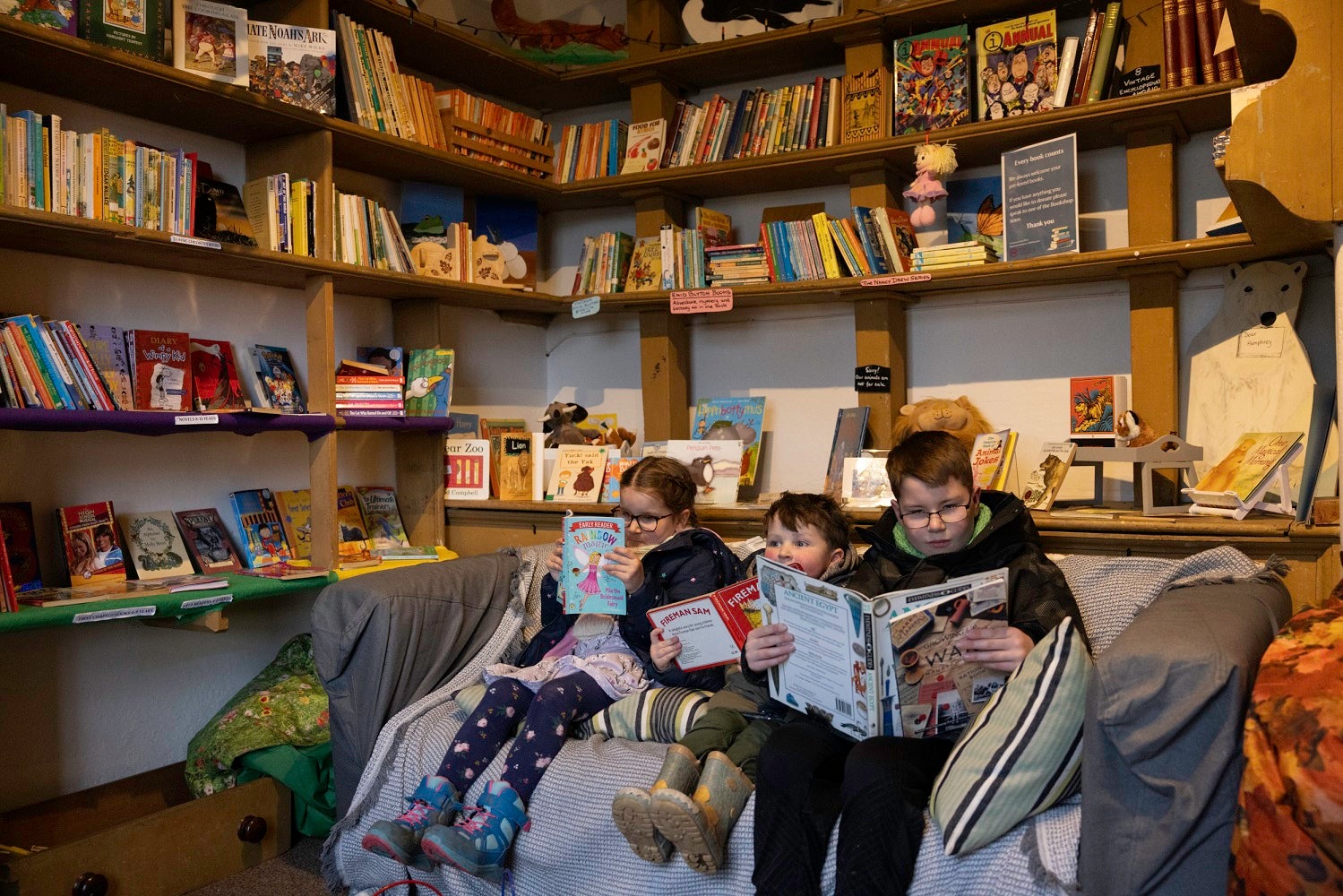 Three children sat on sofa reading in second hand bookshop at Ormesby Hall