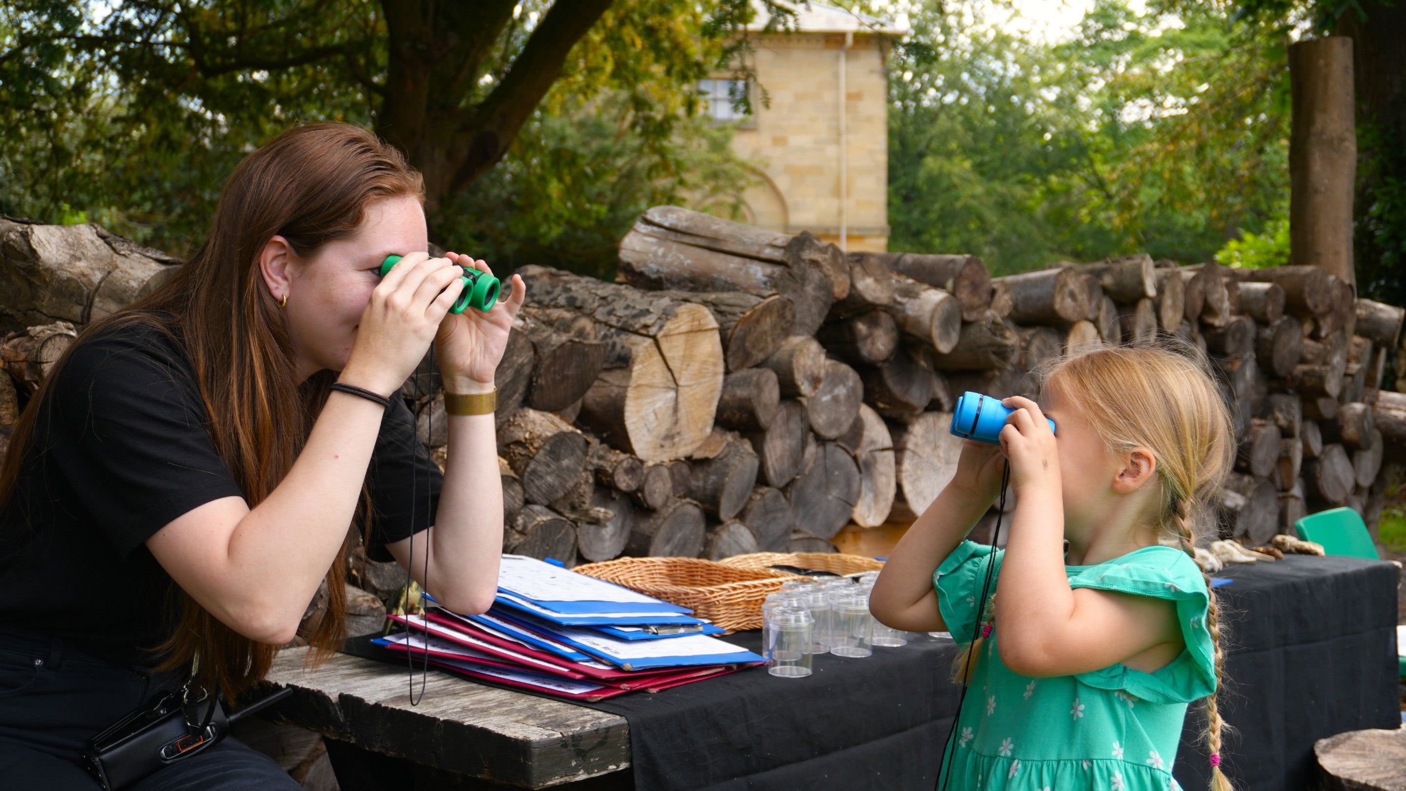 A National Trust staff member interacting with a young girl by looking at each other with binoculars