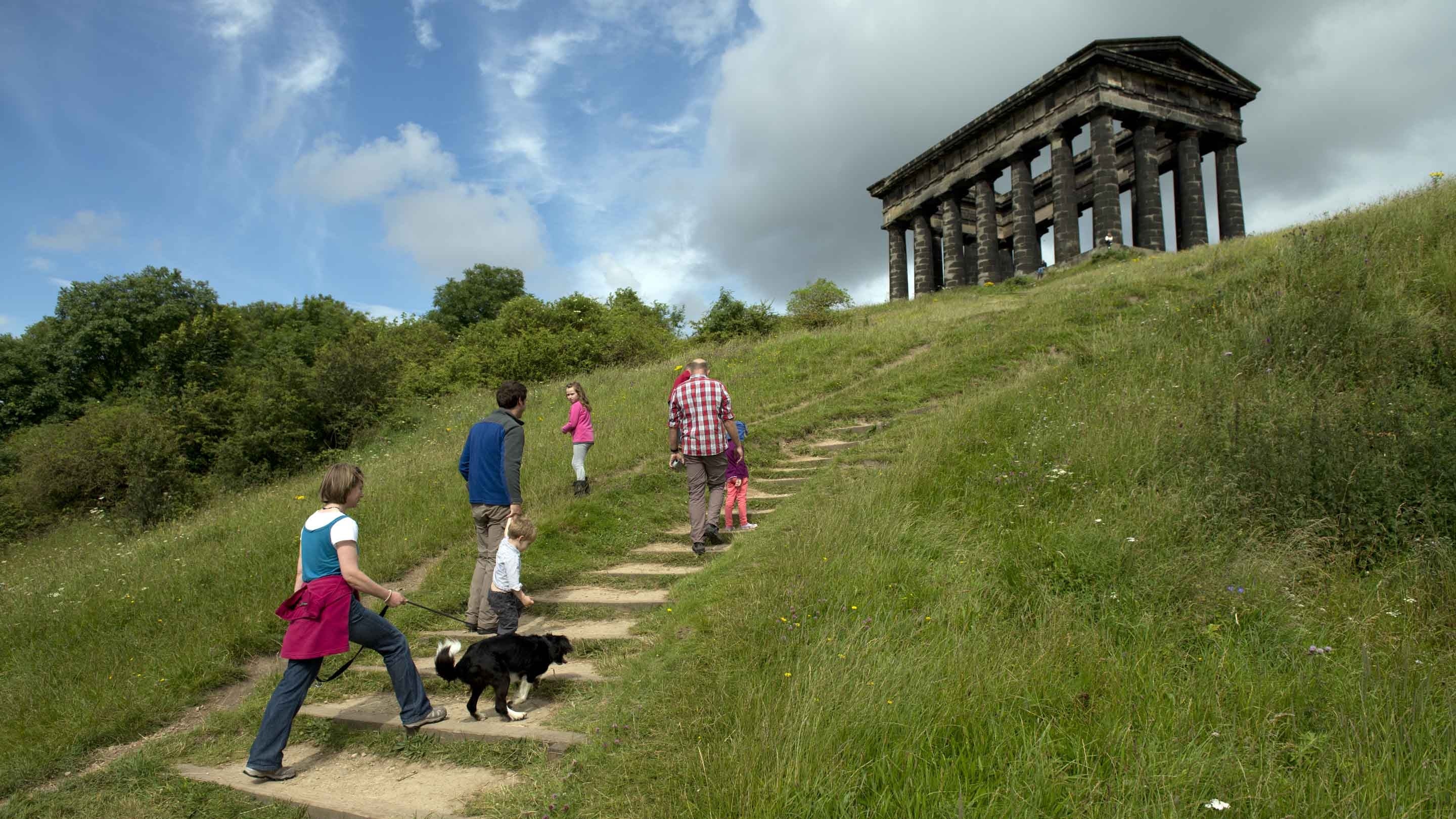 Visitors climb the steps up the grassy mound towards the Doric temple, Penshaw Moument, Sunderland