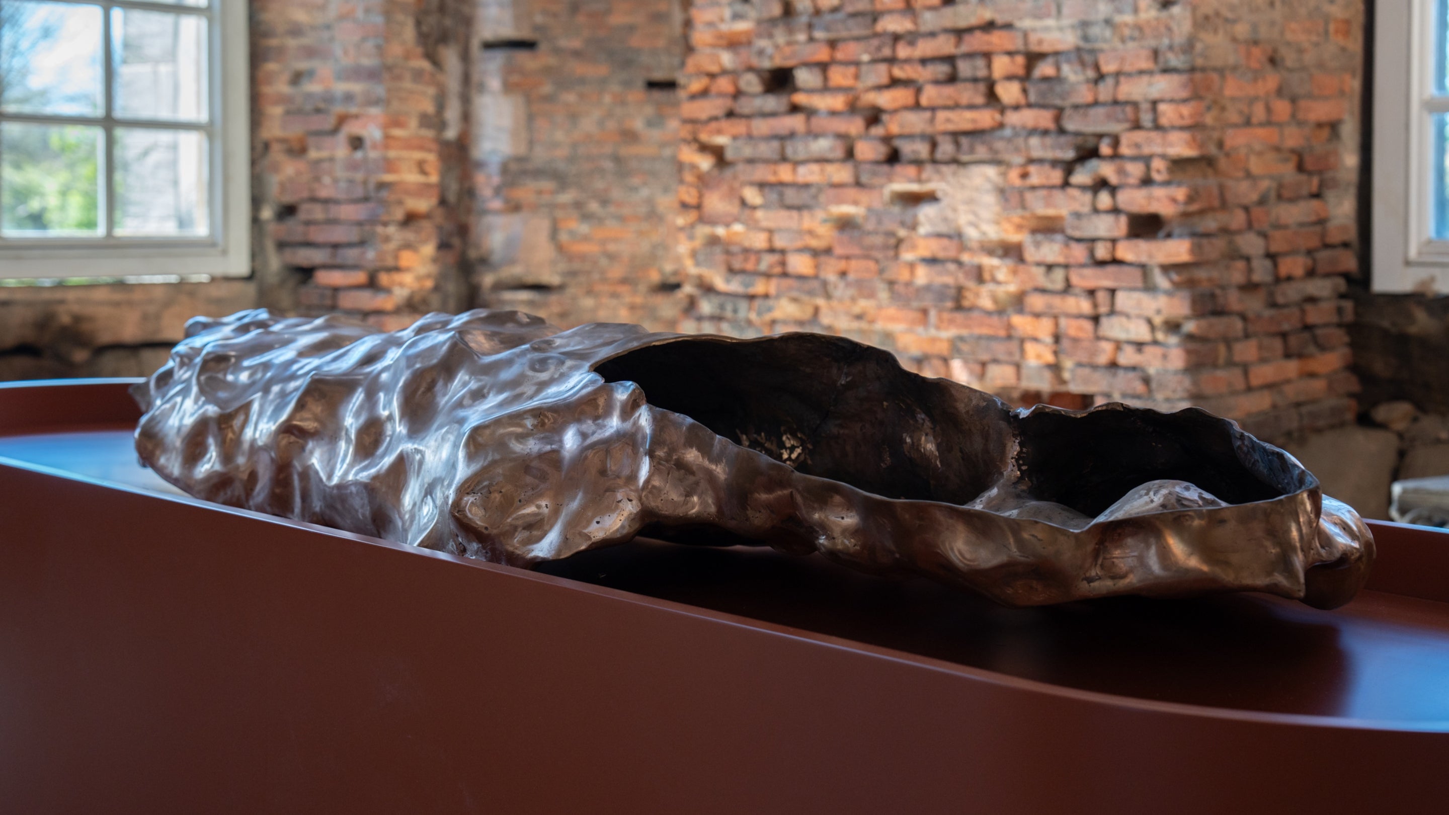A shiny abstract metal sculpture on a bronze plinth