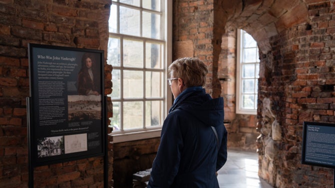A woman stands in front of a series of exhibition panels.