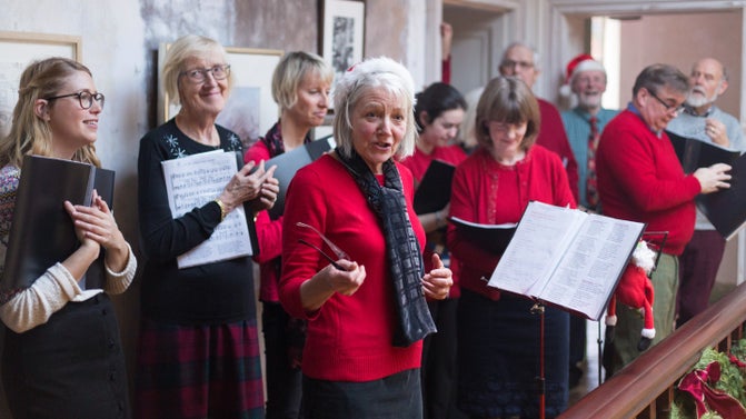 A Christmas choir gathered around a balcony. The choristers are wearing red jumpers.