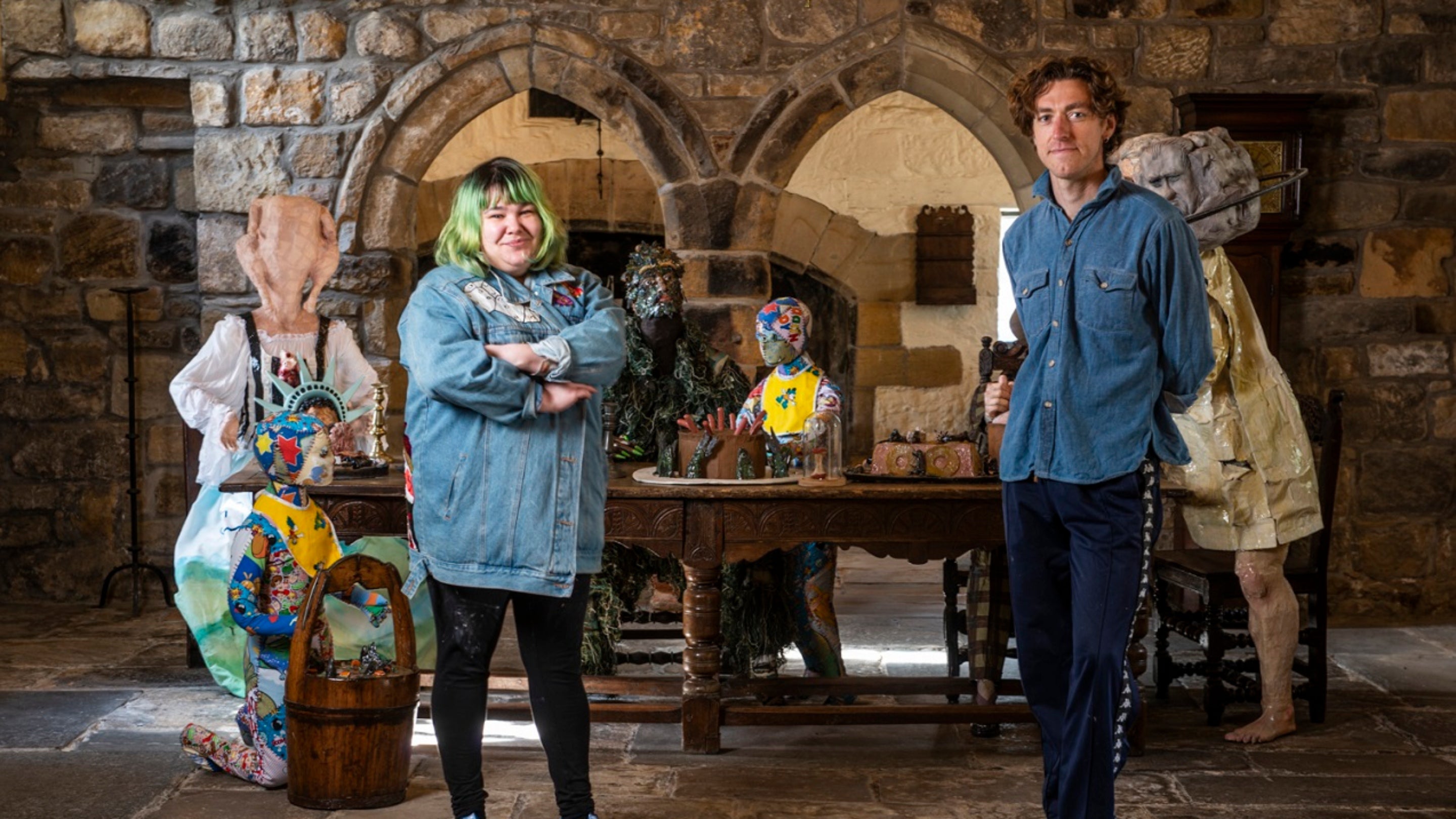 artists Lindsey Mendick and Dominic Watson standing in front of the WASSA exhibition. Seated at the table are a group of colourful characters from folklore, fiction and fact. Featuring a sculpture of Fred Hill, the local historian and schoolmaster who played a key role in saving Washington Old Hall from ruin and president George Washington, who’s ancestors once lived here.