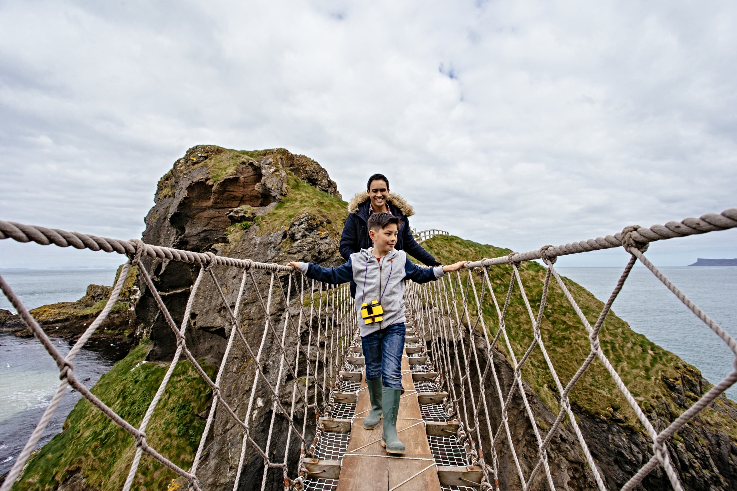 A man and a young boy crossing Carrick-a-Rede Rope Bridge