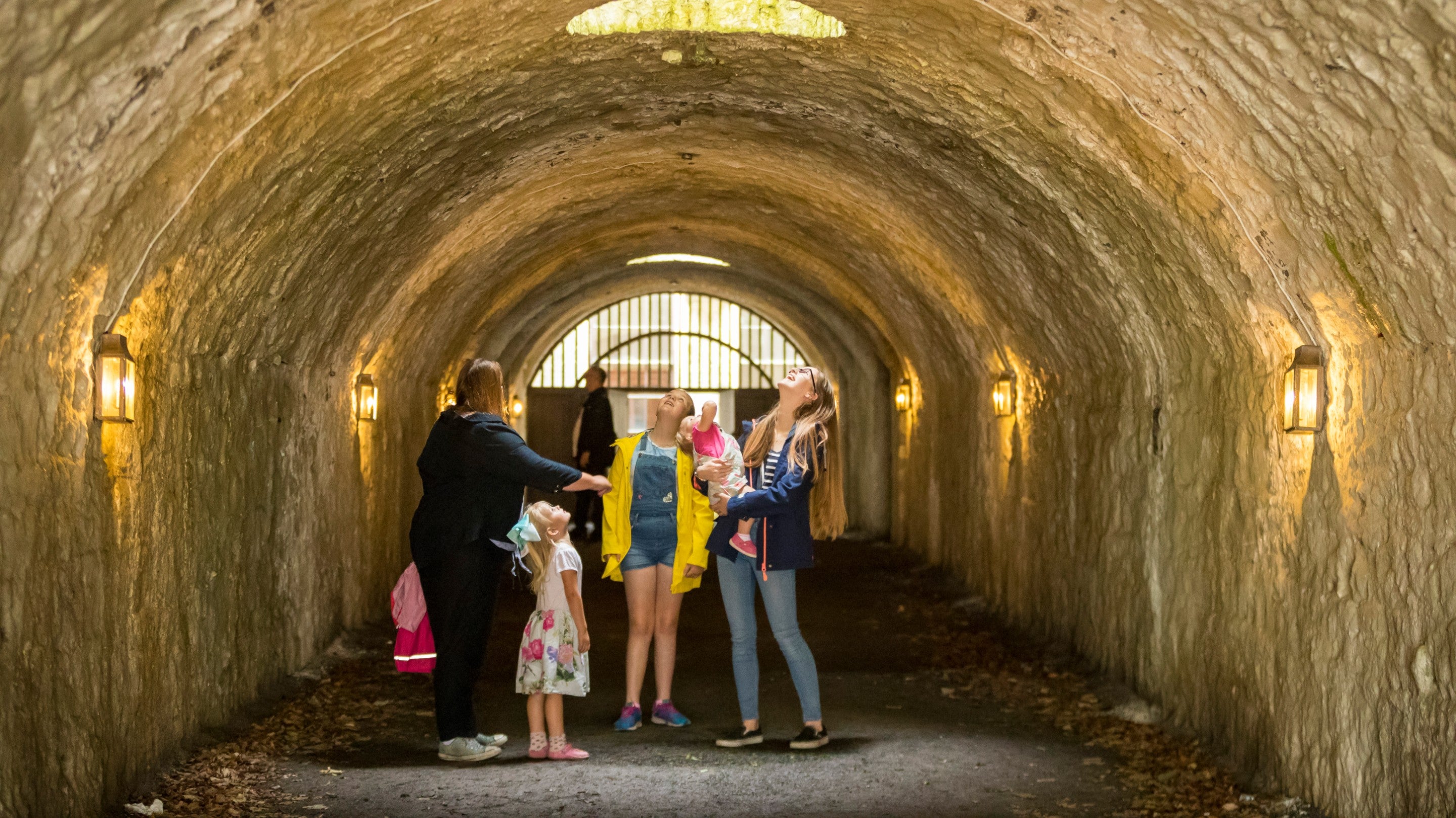 A family exploring the stone-vaulted tunnel in the Basement at Castle Coole, County Fermanagh