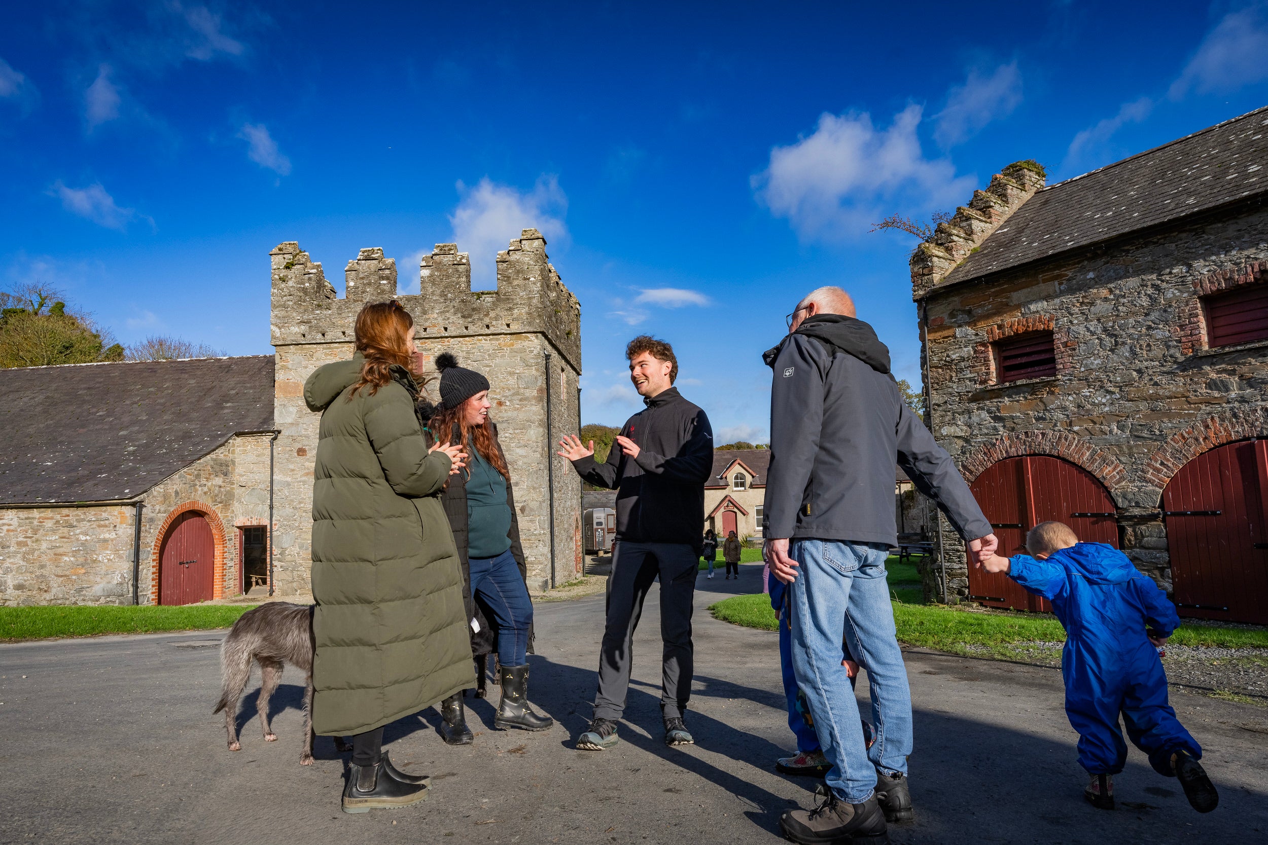 Staff talking with visitors at Castle Ward in the farmyard